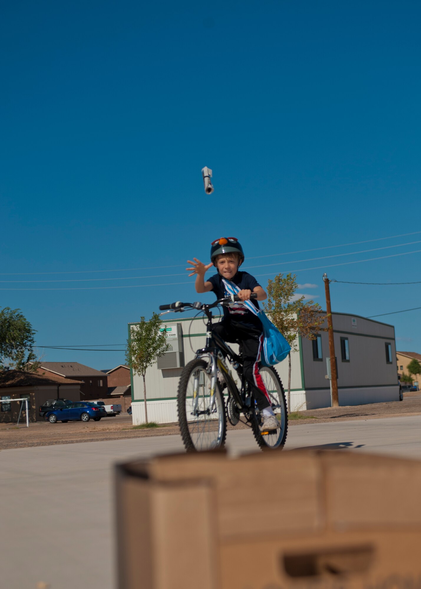 Alex Bennett, son of Col. Kevin Bennett, 49th Mission Support Group commander, simulates running a newspaper route during the Bike Rodeo at Holloman Air Force Base, N.M., Aug. 7. The Bike Rodeo program teaches children about safe riding habits and proper use of protective equipment by engaging them with safety scenarios and skill games. (U.S. Air Force photo by Airman 1st Class Aaron Montoya/Released)