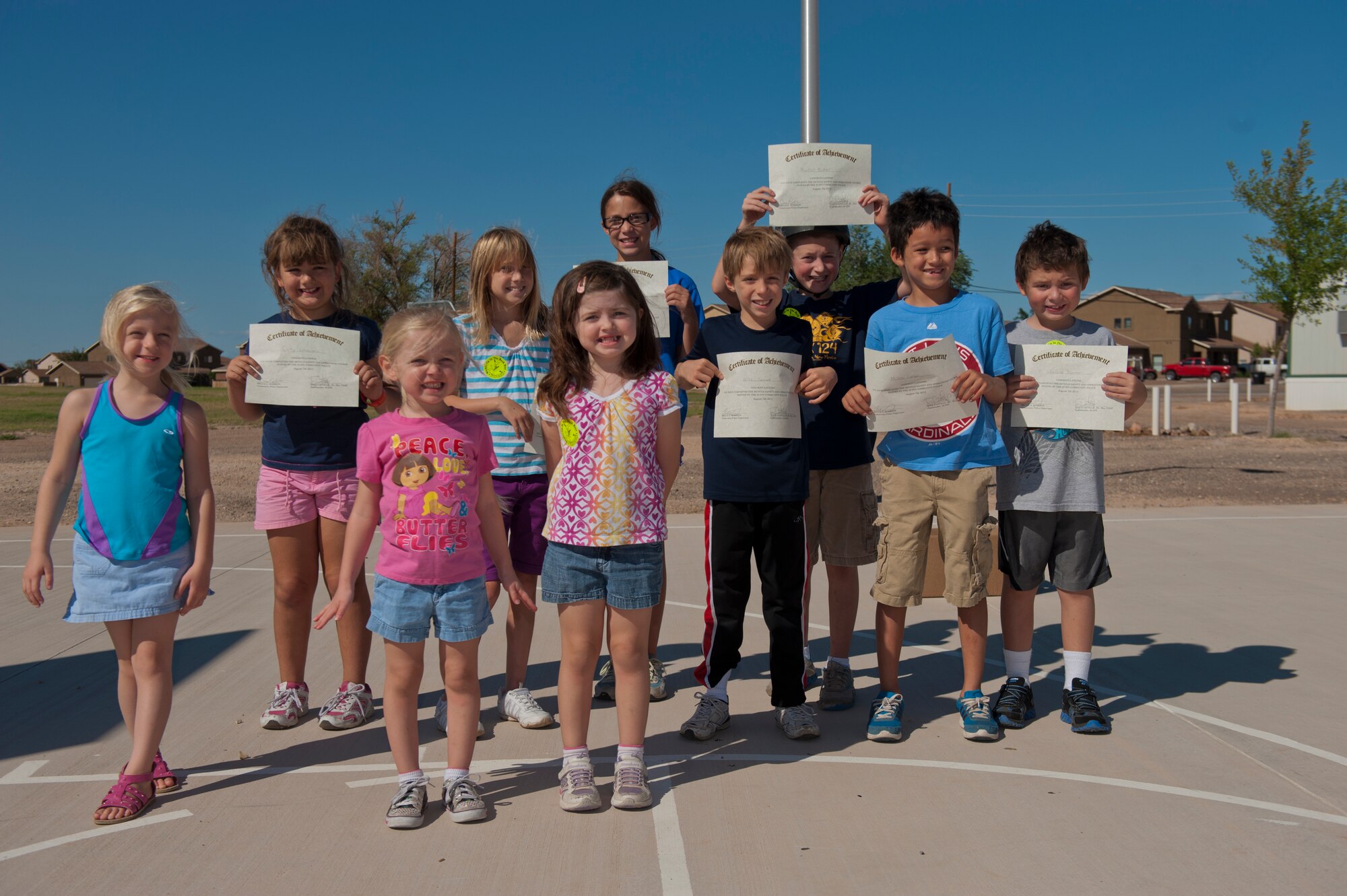 Team Holloman dependants display their certificates after completing the Bike Rodeo at Holloman Air Force Base, N.M., Aug. 7. The Bike Rodeo program teaches children about safe riding habits and proper use of protective equipment by engaging them with safety scenarios and skill games. (U.S. Air Force photo by Airman 1st Class Aaron Montoya/Released)