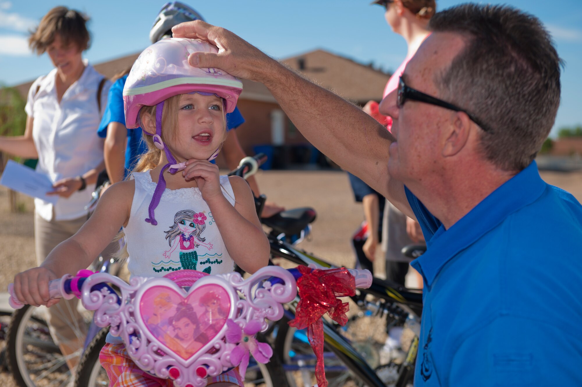 Bruce Roberts, 49th Security Forces Squadron Community Police officer, checks a child’s helmet to ensure it fits properly during the bi-annual Bike Rodeo at Holloman Air Force Base, N.M., Aug. 7. The Bike Rodeo program teaches children about safe riding habits and proper use of protective equipment by engaging them with safety scenarios and skill games. (U.S. Air Force photo by Airman 1st Class Aaron Montoya/Released)