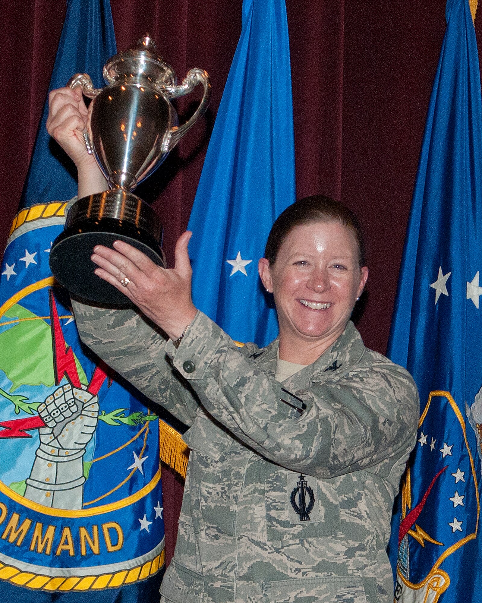 Col. Tracey Hayes, 90th Missile Wing commander, hoists the Omaha Trophy above her head after it was presented to the wing July 30, 2013, in the Base Theater. (U.S. Air Force photo by R.J. Oriez)