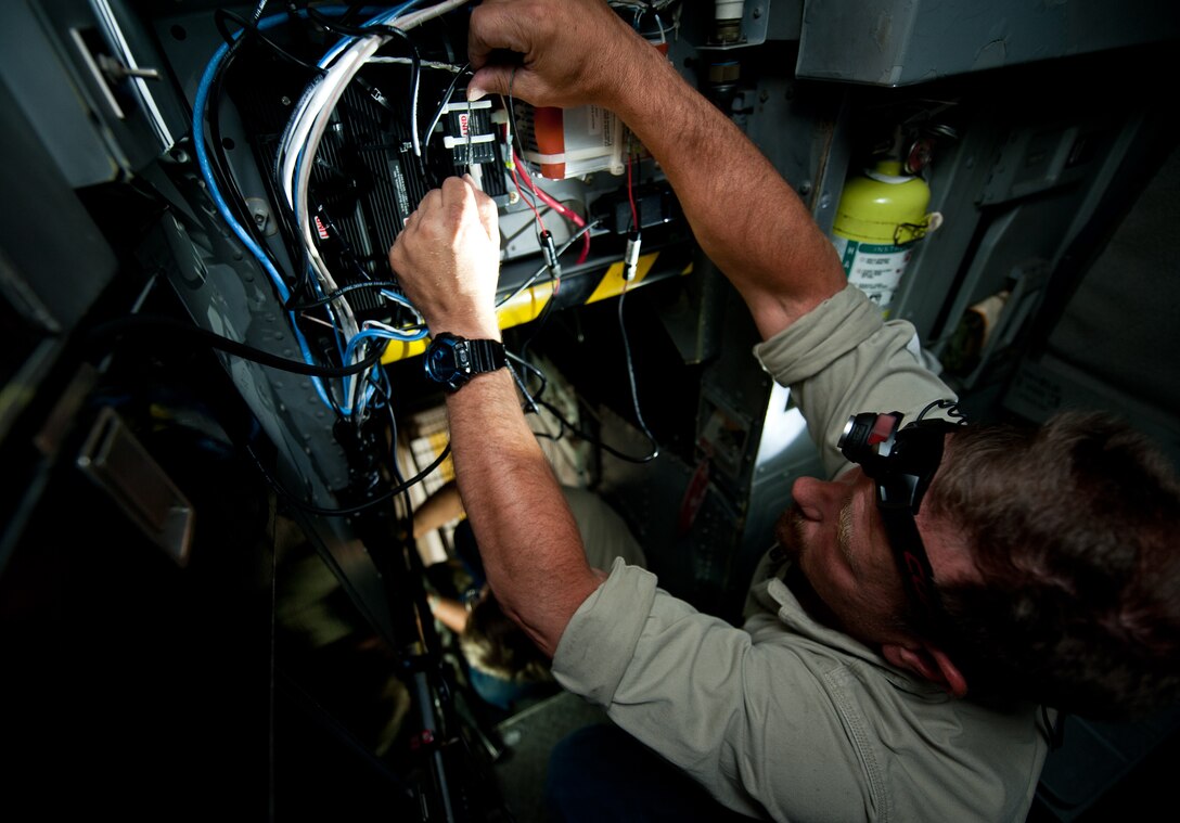 Nathan Lange, 28th Aircraft Maintenance Squadron avionics technician, installs a new display screen in the back of the B-1 cockpit for a trial test of a temporary modification at Ellsworth Air Force Base, S.D., Aug. 6, 2013. The modification equips aircrews with the capability to view moving ground maps on a color display and video from the sniper pod to identify targets. (U.S. Air Force photo by Airman 1st Class Alystria Maurer/Released)