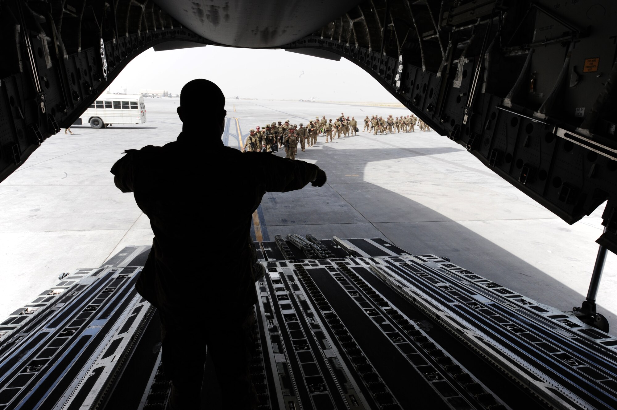 Tech. Sgt. Dequan Barthell, 817th Expeditionary Airlift Squadron Detachment 1, loadmaster evaluator, guides service members into a C-17 Globemaster III in Kandahar, Afghanistan, July 25, 2013. The aircrew’s mission was to return the service members to Transit Center at Manas, Kyrgyzstan as part of the TC’s onward movement mission pillar. (U.S. Air Force photo/Staff Sgt. Krystie Martinez)