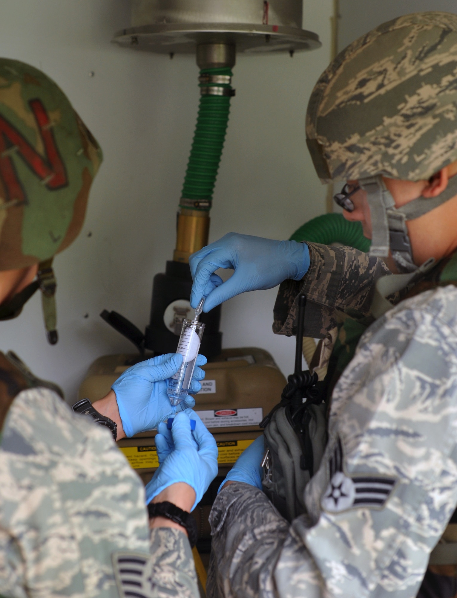 Senior Airman Sean McKeel, right, 51st Civil Engineer Squadron readiness and emergency management journeyman, retrieves buffer solution from Staff Sgt. Mark Olsen, 51st Aerospace Medicine Squadron bioenvironmental engineering technician, while checking a dry filter unit during Operational Readiness Exercise Beverly Midnight 13-03 at Osan Air Base, Republic of Korea, Aug.9, 2013. The solution is used to extract any particles that are in the filter paper for presumptive identification of biological agents. (U.S. Air Force photo/Senior Airman Kristina Overton)