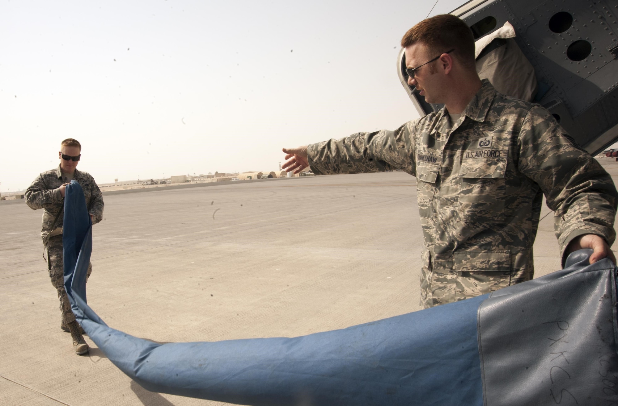 Staff Sgts. Henry Crankshaw and Kevin Morse fold the cooling sock they designed and created, which improves the airflow of mobile air conditioning and heating units on KC-135 Stratotankers prior to take off at the 379th Air Expeditionary Wing Aug. 7, 2013, in Southwest Asia. Crankshaw and Morse are the 379th Expeditionary Operations Support Squadron aircrew flight equipment NCO in charge and assistant NCO in charge. 