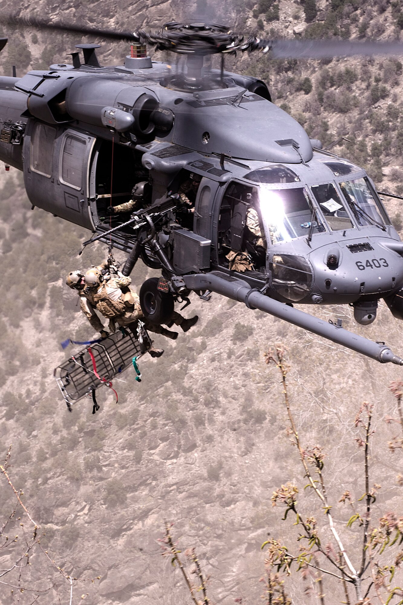 Coalition Special Operations Forces pararescue jumpers lower a stretcher during a medical evacuation in Nuristan province, Afghanistan, April 13, 2012. Then U.S. Air Force Staff Sgt. Mark A. Smith, 33rd Rescue Squadron flight engineer, is pictured here hoisting the PJs down. Afghan National Army Commandos and Coalition SOF, the first to visit that area in more than two years, defeated enemy forces threatening to overrun a village. Smith died when the HH 60G Pave Hawk helicopter in which he was flying went down during a training mission Aug. 5, 2013. (U.S. Navy photo by Mass Communication Specialist 2nd Class Clay Weis/Released)