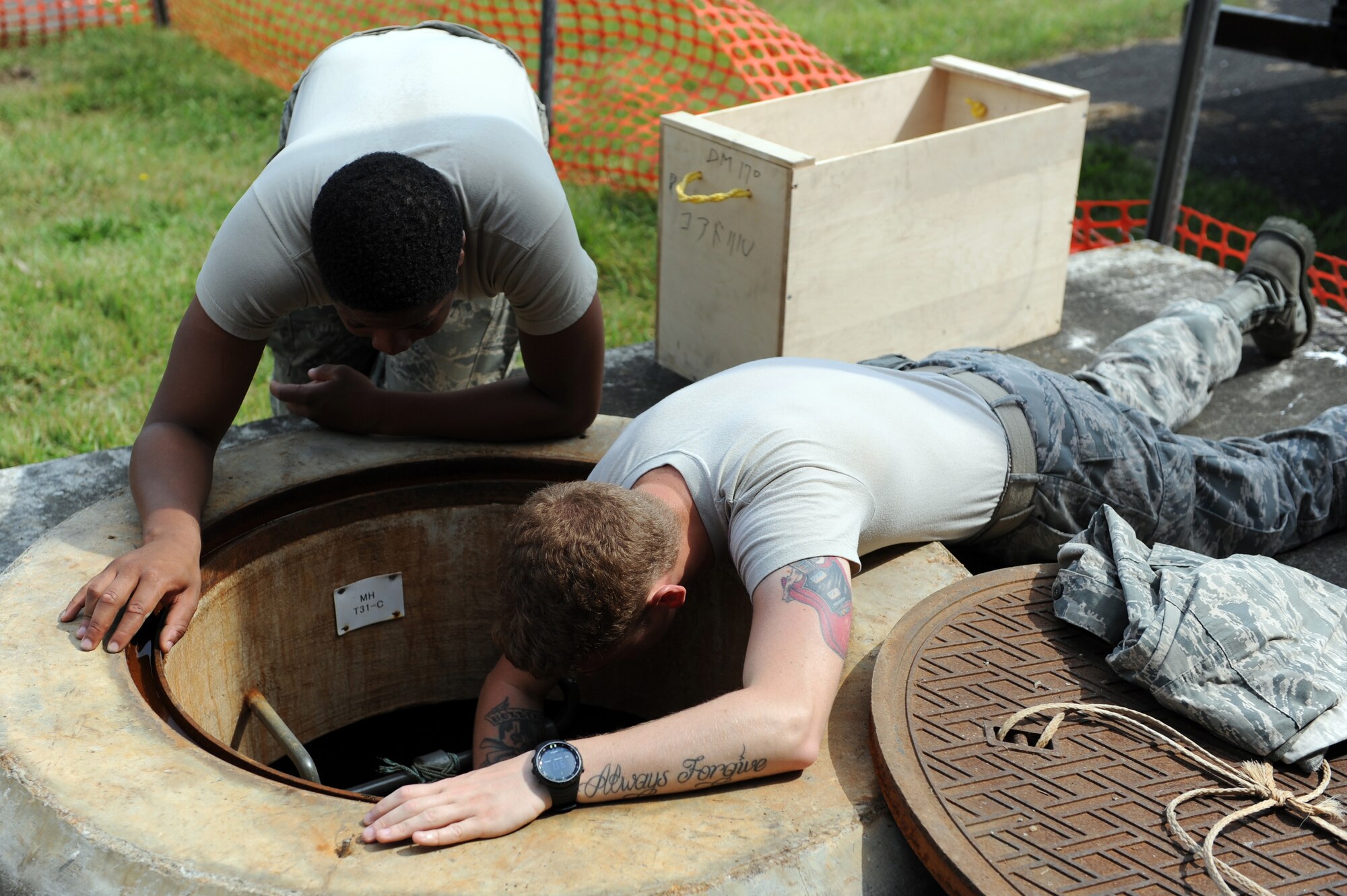 U.S. Air Force Airman 1st Class Skylair Hollie, left, 35th Civil Engineer Squadron electrical systems apprentice, and Senior Airman Hunter Stom, 35 CES structural journeyman, assess the layout of a manhole at Misawa Air Base, Japan, Aug. 8, 2013. Stom and Hollie were discussing the best place to drill a hole to run a conduit through for the base's high-speed internet upgrade. (U.S. Air Force photo by Senior Airman Kia Atkins)