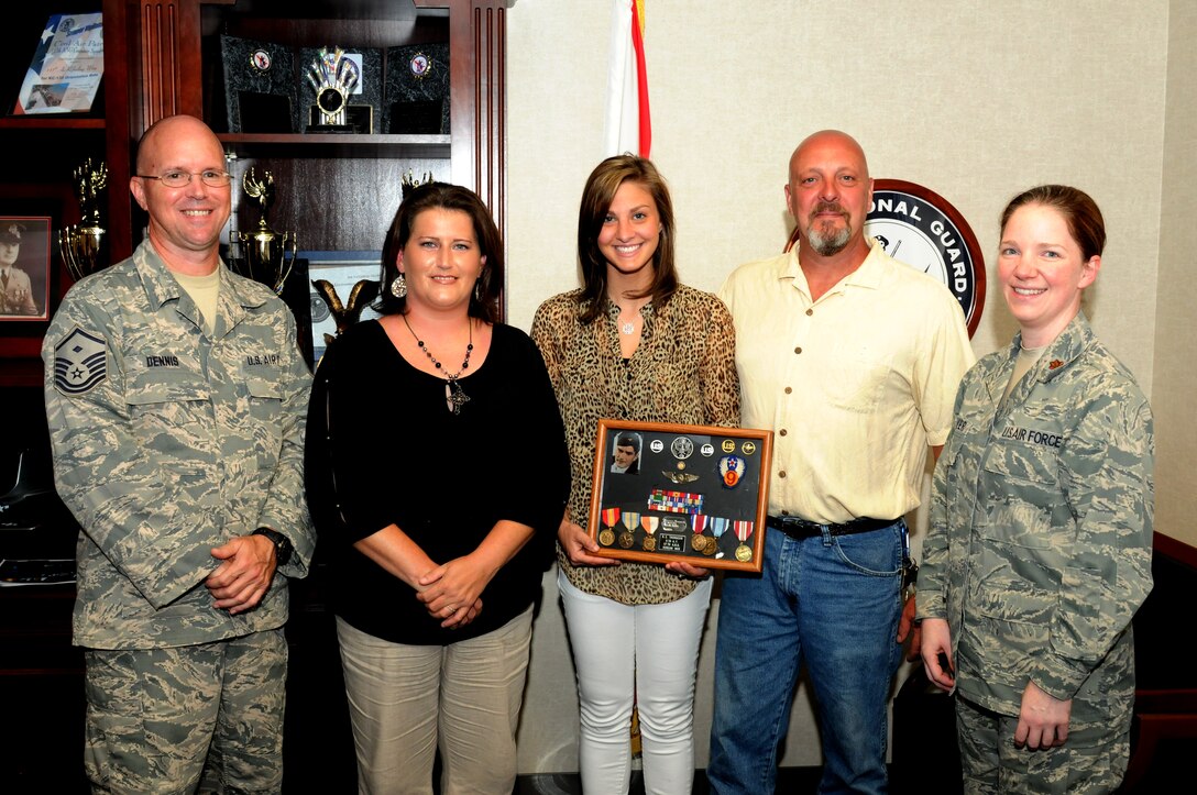 BIRMINGHAM, Ala. -- The Thomason family receives the shadow box of Richard Thomason from Kerry Blow. Blow found the shadow box in the false bottom of an antique chest she purchased to store quilts in. Richard Thomason was a firefighter at the 117th Air Refeuling Wing from 1948 to 1972. (U.S. Air National Guard photo by Master Sgt. David Maxwell) 