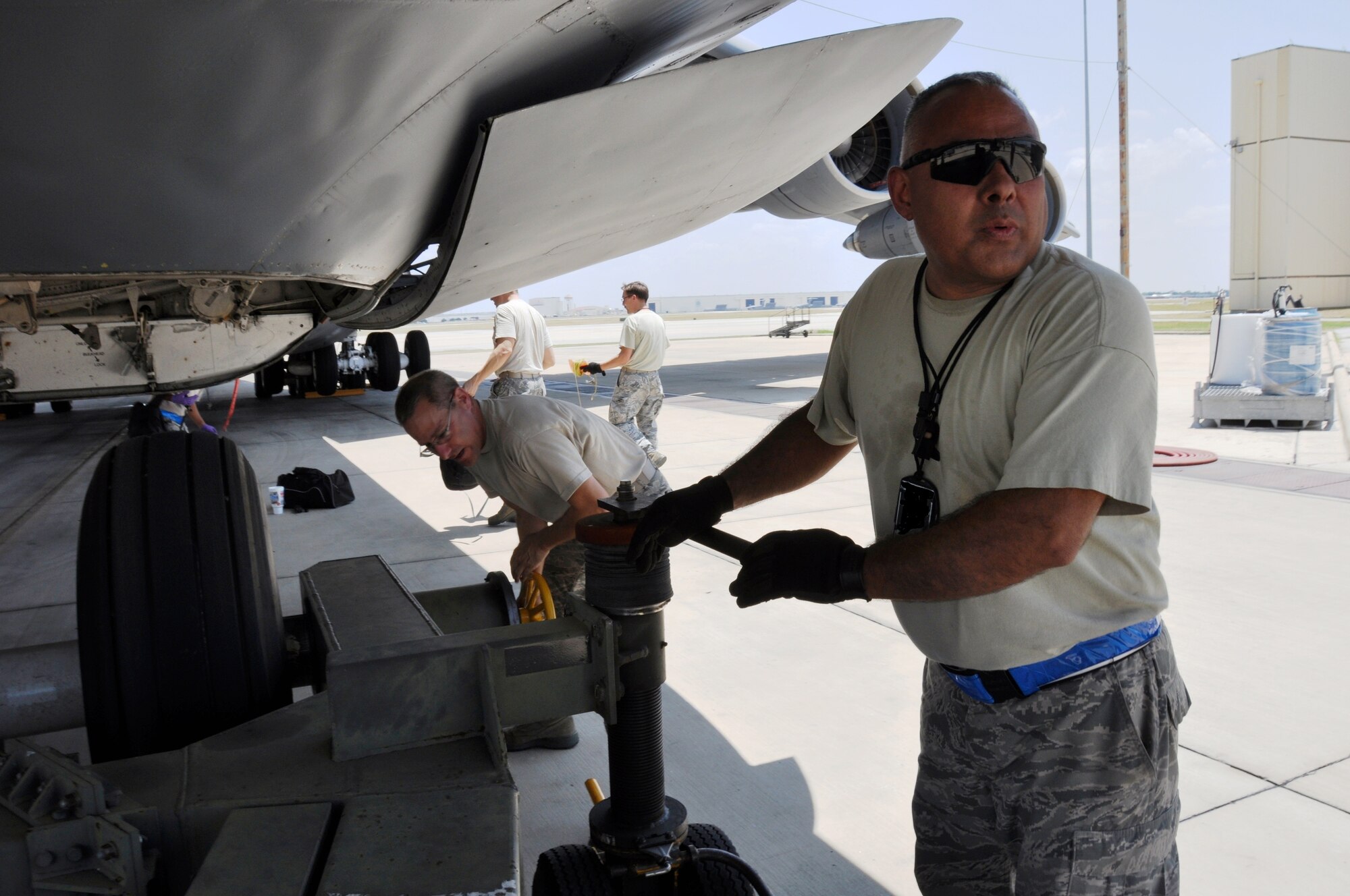 Working in the shade of a plane offers some protection to Tech Sgt. Robert Espinoza, a 433rd Aircraft Maintenance Squadron crew chief, as he prepares a C-5A Galaxy for towing on the flight line here Aug. 10. Temperatures in the San Antonio area reached 100 degrees five days in a row. While on the flight line, temperatures are 15-20 degrees hotter due to the concrete. (U.S. Air Force photo by Tech Sgt. Carlos J. Trevino)