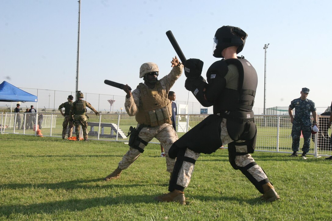 Gunny Sgt. Octavius Shivers, left, and Cpl. Jonathan Kirkman, right, demonstrates non-lethal fighting techniques at the National Night Out event aboard Naval Air Station Sigonella, Italy, Aug. 6, 2013. Marines and sailors with Special-Purpose Marine-Air Ground Task Force Africa 13 participated in the event with a static display of weapons, both lethal and non-lethal. Special-Purpose MAGTF Africa continues to build relationships with the community while simultaneously strengthening U.S. Africa Command and U.S. Marine Corps Forces Africa's ability to assist partner nations in addressing security challenges in the region. (U.S. Marine Corps photo by 1stLt Tatiana Zappardino/Released)