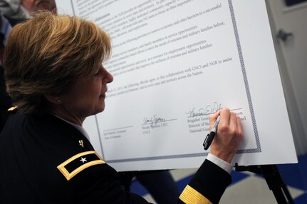 Army Brig. Gen. Marianne Watson, the director of Manpower and Personnel at the National Guard Bureau, signs the agreement between the NGB and the Corporation for National Community Service March 13, 2013, in Wilmington, Del., for the NGB Joining Community Forces initiative. The new initiative is a community level, grass roots solution program that expands on the Joining Forces campaign of first lady Michelle Obama and Dr. Jill Biden. JCF focuses on supporting all service members, families, and veterans in the areas of employment, education, across all components.