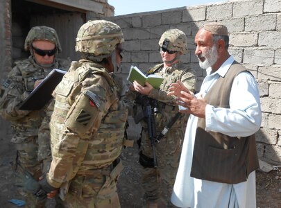 Victoria Burke of the Civilian Expeditionary Workforce speaks with Abdul Baqi Hikmat about his poultry-feed production in Kandahar Province, Mar. 13, 2013.