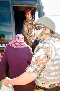 Assisted by Jordan Armed Forces members, a Syrian refugee boards a bus at Tal shehab Reception Center near Ash Shajarah in northern Jordan, April 2, 2013.