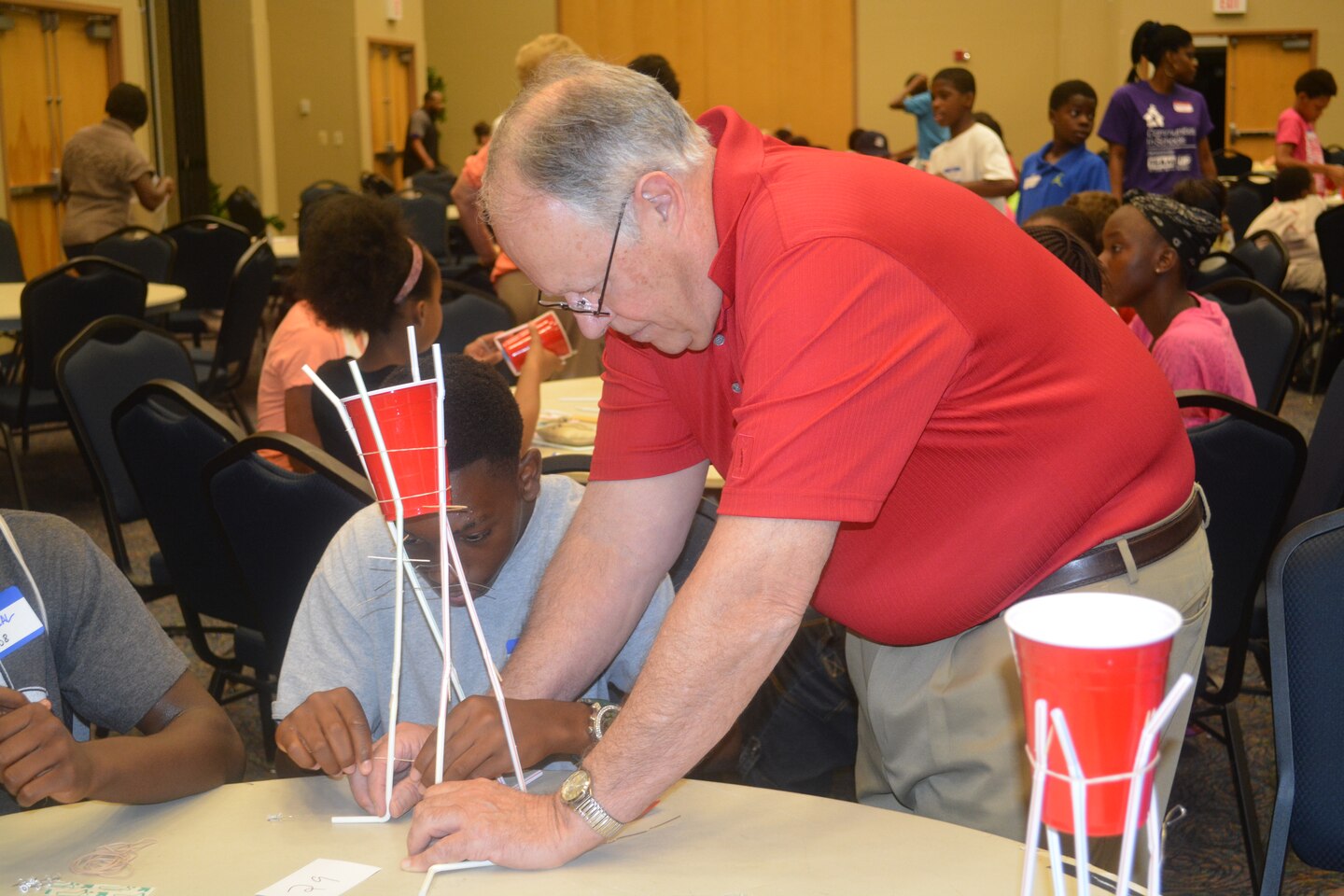 Under the watchful eye of Joe Tavares, civil engineer in the Construction Division, students apply the finishing touches to their water tower design. 