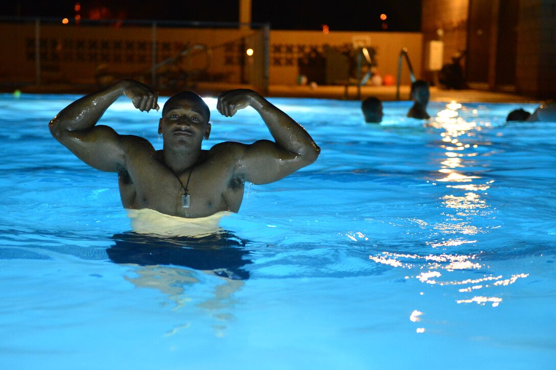 U.S. Air Force Airman 1st Class Andrew Chestnutt, 27th Special Operations Support Squadron, flexes his muscles in the DZ Pool during a pool party Aug.10, 2013 at Cannon Air Force Base, N.M. The luau-themed party allowed them to partake in the aquatic center's features until almost midnight. (U.S. Air Force photo/ Airman 1st Class Eboni Reece)