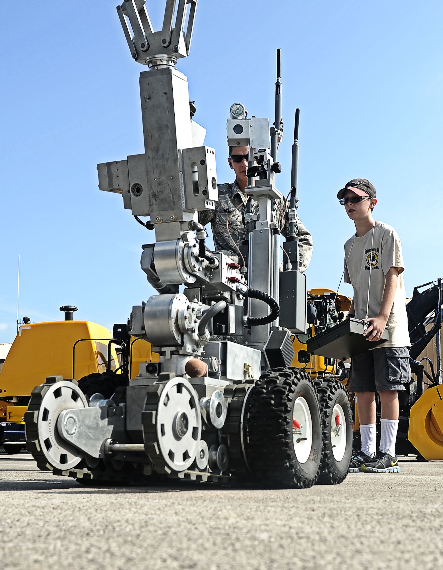 Senior Airman Joel Mixon, 375th Civil Engineer Squadron explosive ordinance disposal technician, watch Alex Bendele operate the EOD robot Aug. 9, 2013 at Scott Air Force Base, Ill.  The CES hosted a back to school event for Team Scott family members to come out, observe and play with som eof the equiptment used by CE. (U.S. Air Force photo/Senior Airman Divine Cox)