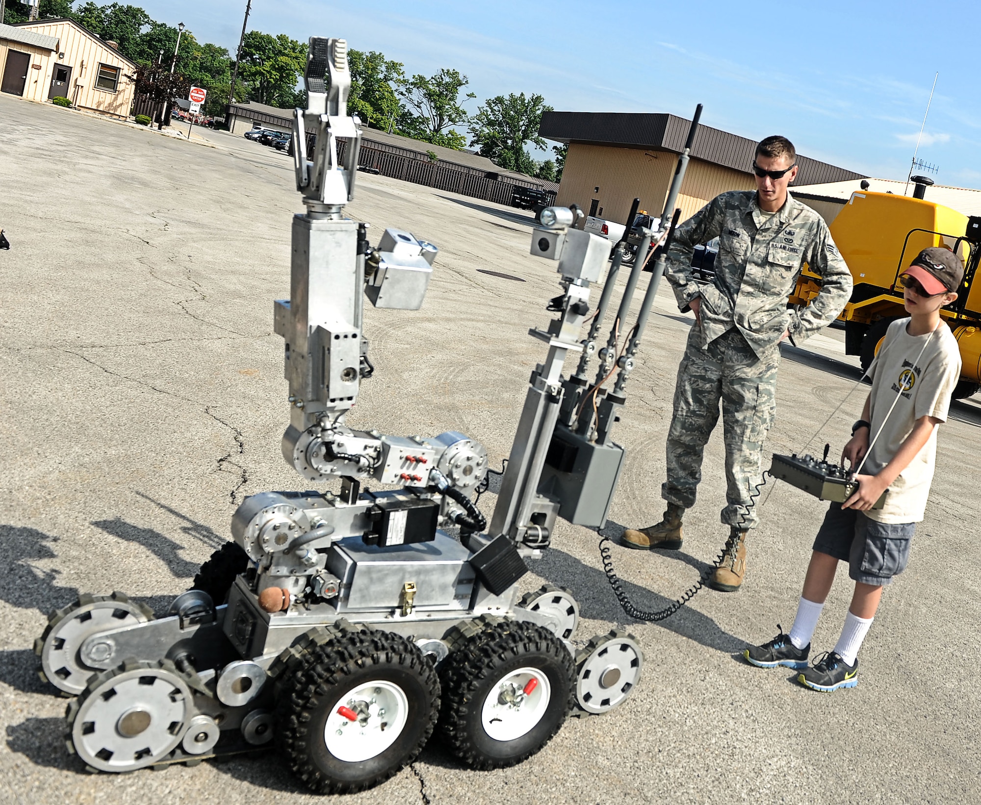 Senior Airman Joel Mixon, 375th Civil Engineer Squadron explosive ordinance disposal technician, watch Alex Bendele operate the EOD robot Aug. 9, 2013 at Scott Air Force Base, Ill.  The CES hosted a back to school event for Team Scott family members to come out, observe and play with som eof the equiptment used by CE. (U.S. Air Force photo/Senior Airman Divine Cox)