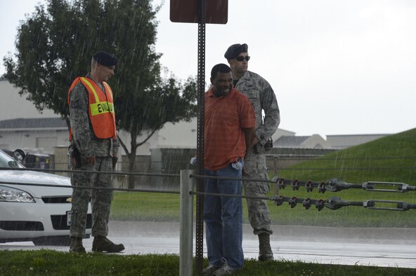 An exercise evaluator watches Staff Sgt. Che Mason, (foreground) of the 436th Aerial Port Squadron, as he is held by Senior Airman Sean Shields, 436th Security Forces Squadron after being apprehended following a simulated armed-robbery at building 520, Dover Air Force Base, Del. on August 12, 2013. The purpose of a MARE is to evaluate the local first responder’s ability to respond to a myriad of domestic situations and scenarios. (U.S. Air Force photo/Greg L. Davis)