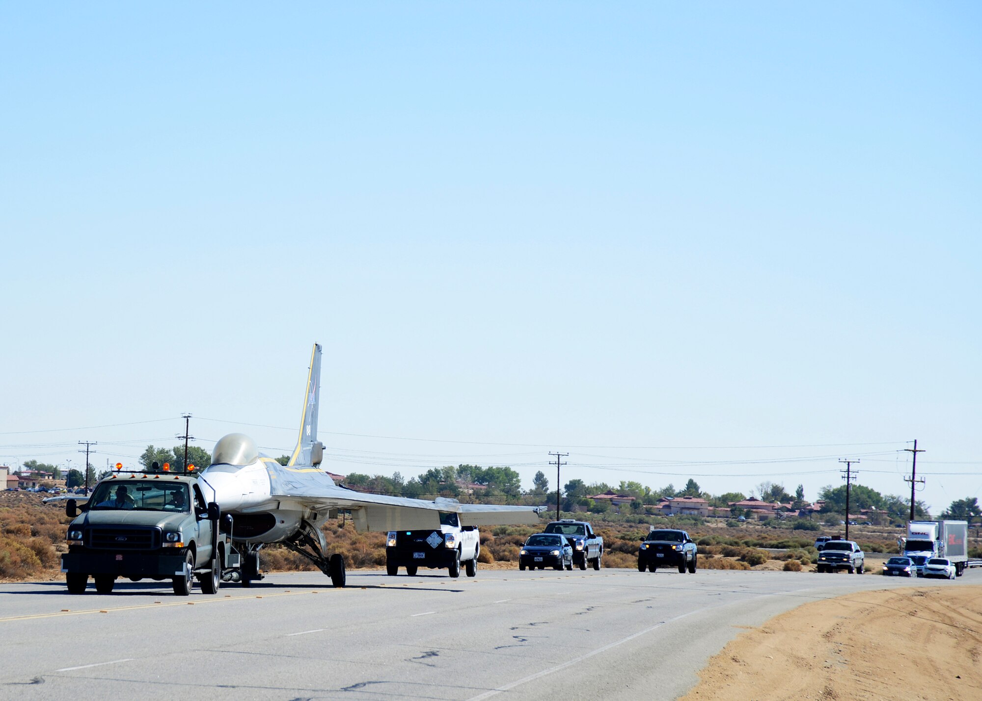 Traffic is stopped as the F-16XL is transported west down Rosamond Blvd. towards its new home at the Air Force Flight Test Museum Aug. 9, 2013.  The F-16XL, an experimental fighter, is a derivative of the F-16 that was used to explore the advanced cranked-arrow delta wing. The plane was one of three aircraft transported to the AFFT Museum from their restoration home in Hangar 1864. (U.S. Air Force photo by Rebecca Amber)