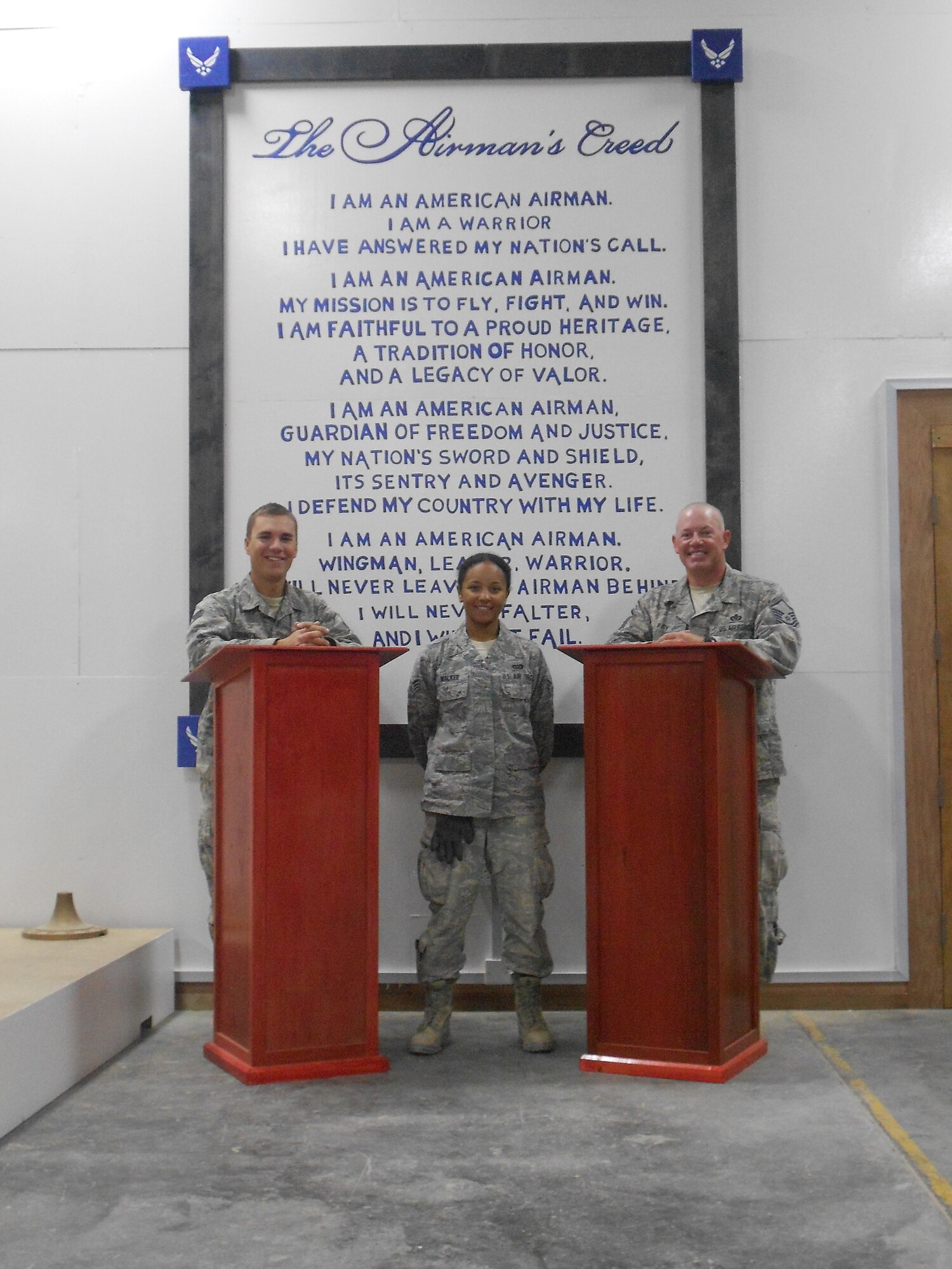 Master Sgt. Kenneth M. Fay, from Luke Air Force Base, and Senior Airmen Patricia Walker and Andrew Brinza, both from Wright-Patterson Air Force Base, designed and built a wall mural with the Air Force Creed and two podiums to be used for monthly promotion and recognition ceremonies and other events at their deployed location in Southwest Asia. (Courtesy Photo)