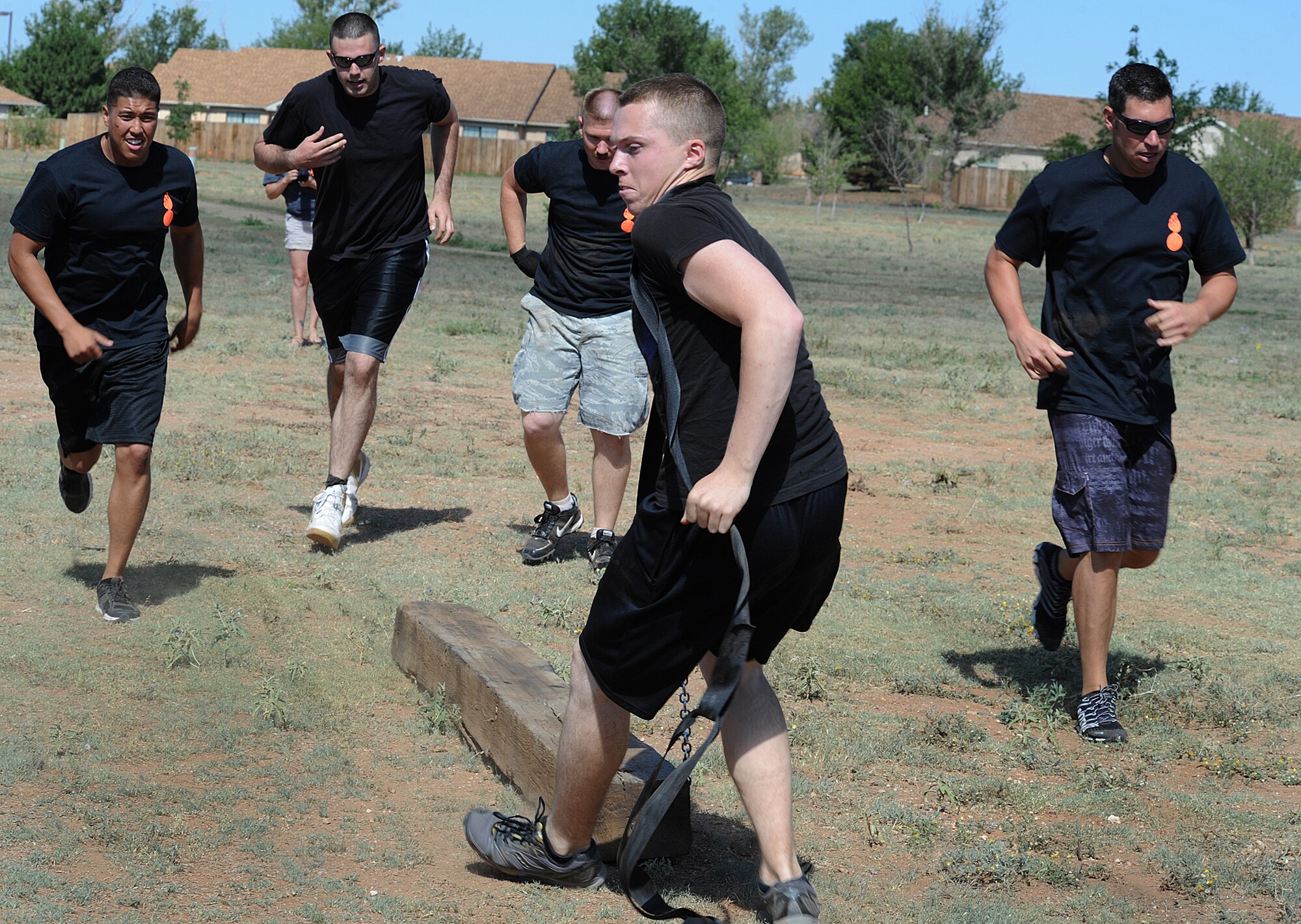 The 27th Special Operations Maintenance Squadron munitions team runs alongside their team member as he pulls a cross-tie toward the end of the course during the Weapons and Ammo competition Aug. 9, 2013 at Cannon Air Force Base, N.M. The competition was a daylong event with games and activities for military members and their families. (U.S. Air Force photo/Senior Airman Ericka Engblom)