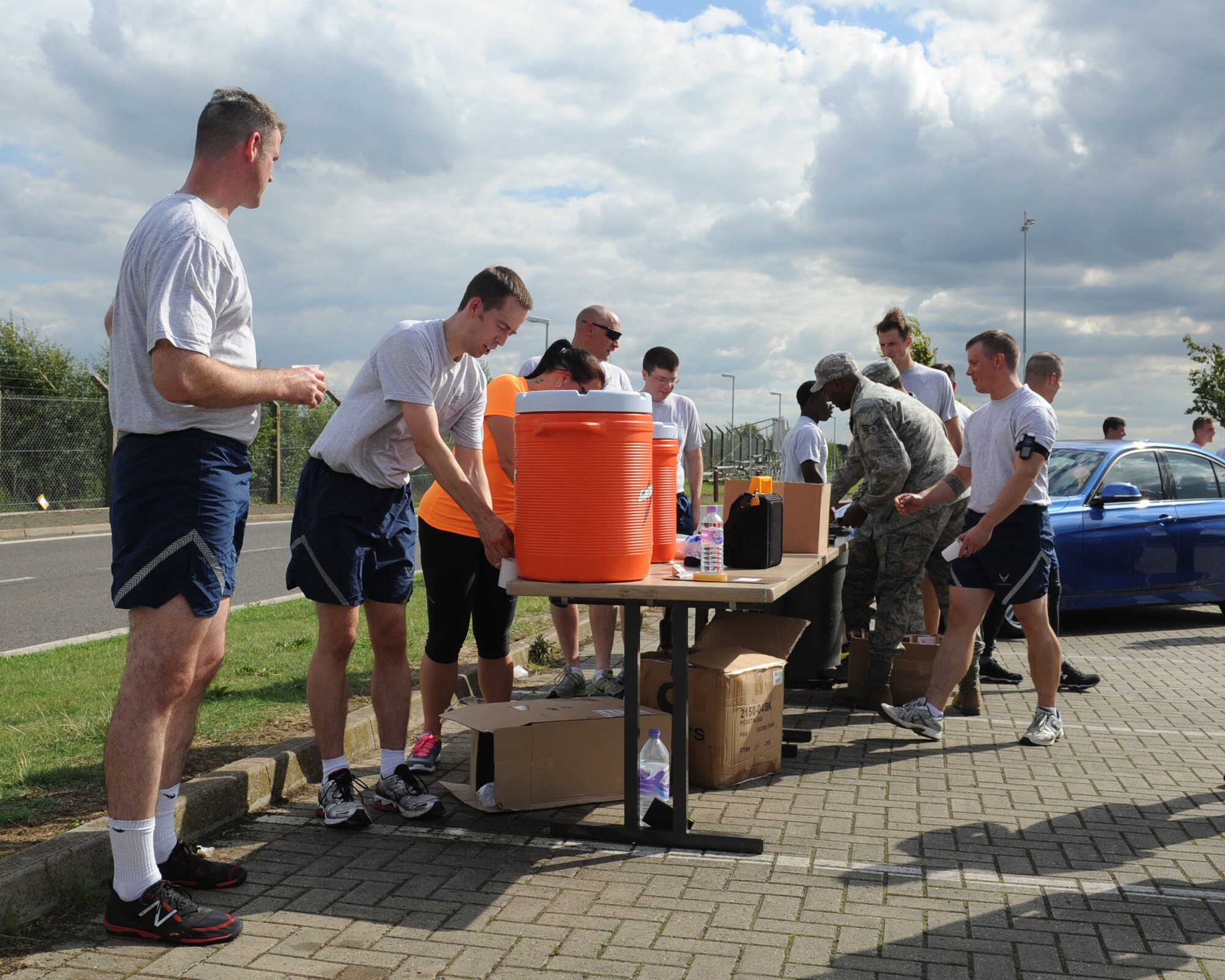 Team Mildenhall members fill cups with water for their wingmen after the monthly 100th Air Refueling Wing 5 km run Aug. 9, 2013, on RAF Mildenhall, England. The monthly run is mandatory for 100th ARW members and open to all Team Mildenhall members. (U.S. Air Force photo by Airman 1st Class Preston Webb/Released)