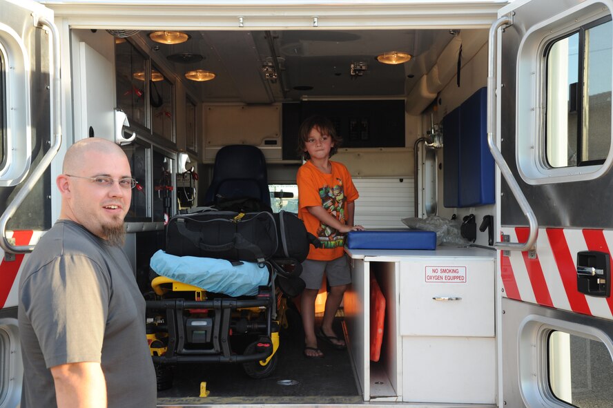 A Luke family member and his child check out the inside of an ambulance provided by the 56th MDG. Squadrons and units from across base brought along military gear used to carry out their mission for family members to have an up-close and personal look. (U.S. Air Force photo/Airman 1st Class Pedro Mota)