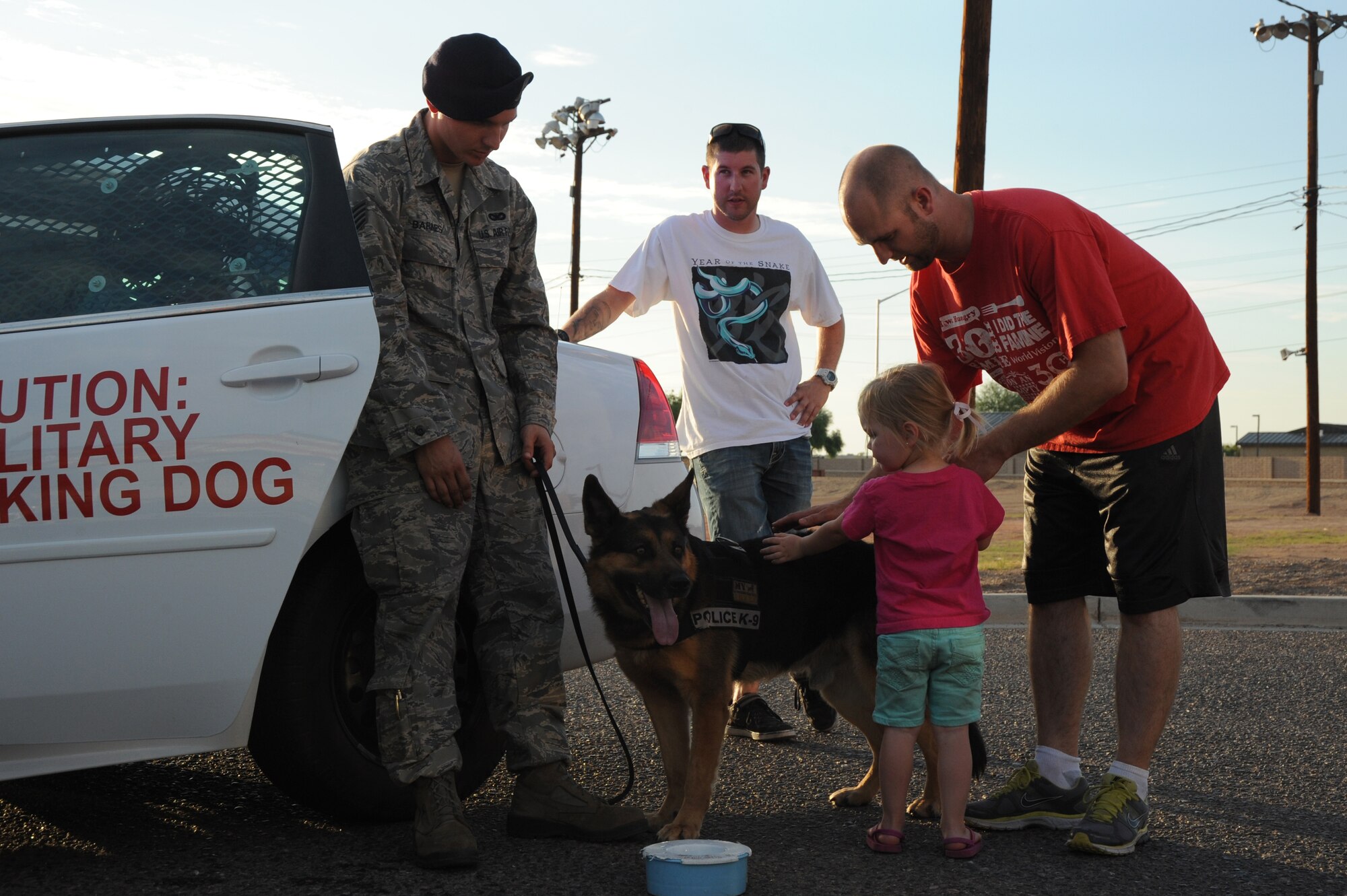 Staff Sgt. Dustin Barnes, 56th Security Forces Squadron Military Working Dog handler, and Maxo greet Luke family members at the Back to School Bash. (U.S. Air Force photo/Airman 1st Class Pedro Mota)