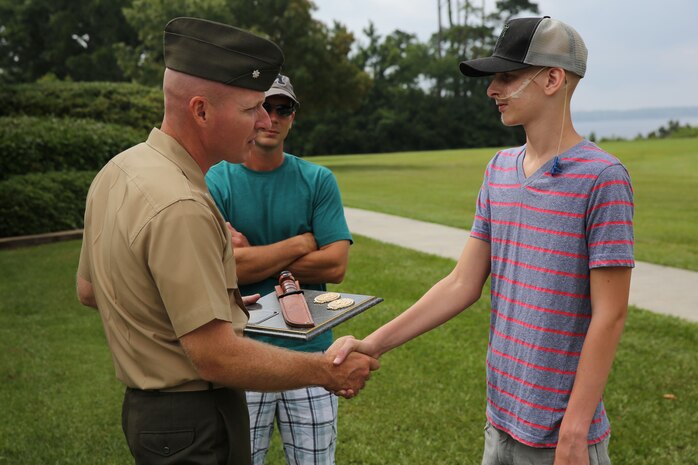 Lt. Col. William Stophel, the Commanding Officer for Combat Logistics Battalion 2, 2nd Marine Logistics Group, awards Austin Saxton a warrior’s plaque, complete with KBAR knife, while Austin’s father, retired Staff Sgt. Dewey Saxton, watches aboard Camp Lejeune, N.C., Aug. 02, 2013. Even though cancer ravaged his body, Austin never stopped fighting, and said like Marines, he never will. (U.S. Marine Corps photo by Cpl. Devin Nichols)