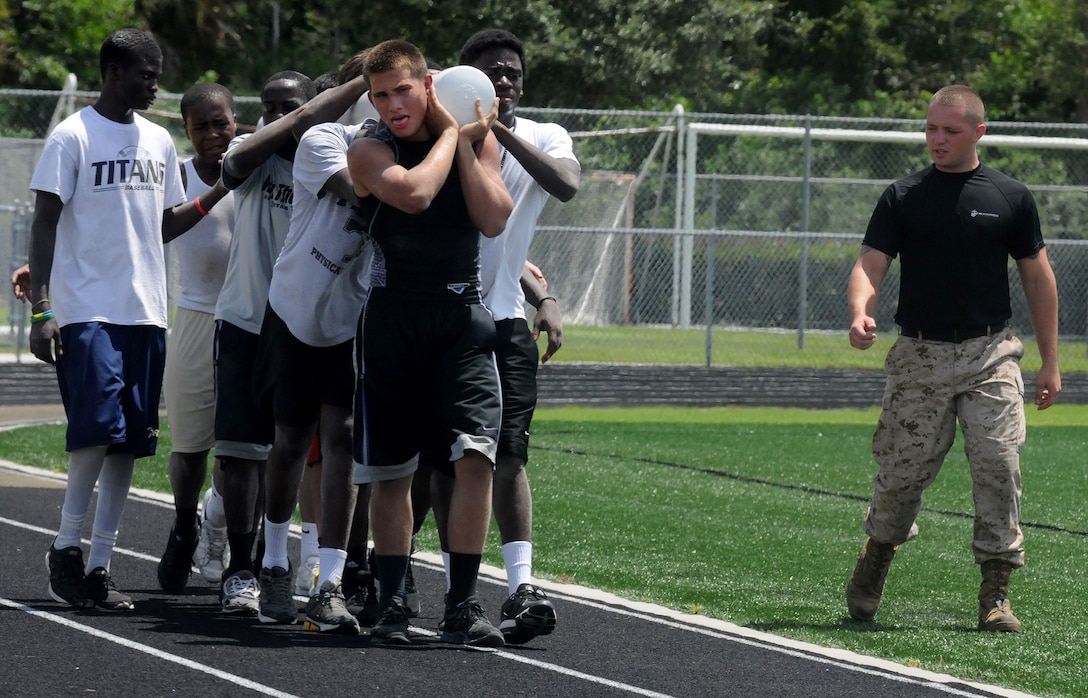 Sgt. Matthew Jacobs (right), a Kentucky native and recruiter from Recruiting Substation Naples, Recruiting Station Ft. Lauderdale, Fla., motivates a group of Golden Gate High School football team members to push through the pain of  physical exhaustion during a rigorous session of circuit training August 3, 2013.  Jacobs was one of eight Marines who helped administer an intensive mentorship program to the team. The three-day camp was put on by the Marines to teach the players leadership and discipline and help them with preparations for the upcoming football season.