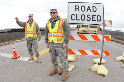 Spc. Bryan Sholts, of Fargo, left, and Spc. Alex Preszler, of Valley City, of the 191st Military Police Company, North Dakota Army National Guard, control traffic in Fargo, April 22, 2013.