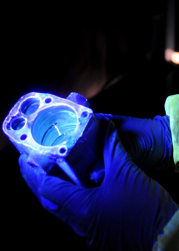 Airman 1st Class Charles Mills, 28th Maintenance Squadron nondestructive inspection technician, inspects a hydraulic accumulator piece under black lights at Ellsworth Air Force Base, S.D., Aug. 9, 2013. Under black light, imperfections appear as green lines allowing NDI to determine the length and location of cracks, aiding in enhancing the maintenance and performance of the B-1. (U.S. Air Force photo by Airman 1st Class Anania Tekurio/Released) 