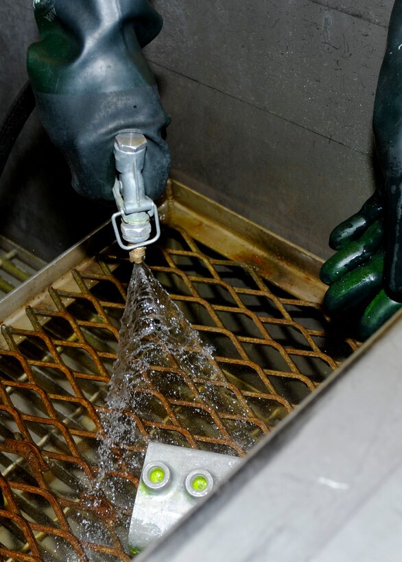 Airman 1st Class Charles Mills, 28th Maintenance Squadron nondestructive inspection technician, rinses excess penetrant liquid off a hydraulic accumulator during a nondestructive inspection process at Ellsworth Air Force Base, S.D., Aug. 9, 2013. The inspection enhances the capability to identify imperfections to aircraft parts -- if any are found, the part is sent to shops on base where they can be fixed or replaced. (U.S. Air Force photo by Airman 1st Class Anania Tekurio/Released)