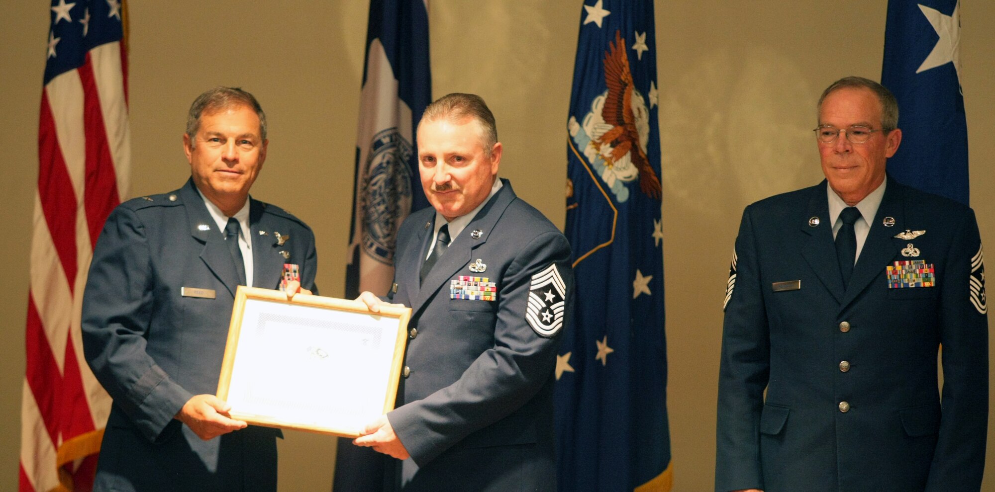 Chief Master Sgt. William G. Whipple accepts a certificate from Brig. Gen. Harold Reed, deputy adjutant general, and assumed position as the new State Command Chief for Wyoming at a transfer of authority ceremony conducted at the Joint Forces Readiness Center Aug. 3, 2013, in Cheyenne, Wyo. Whipple replaces Chief Master Sgt. Ralph D. Hensala (right) who formally retired after the ceremony. (U.S. Army National Guard Photo by Sgt. 1st Class James McGuire)