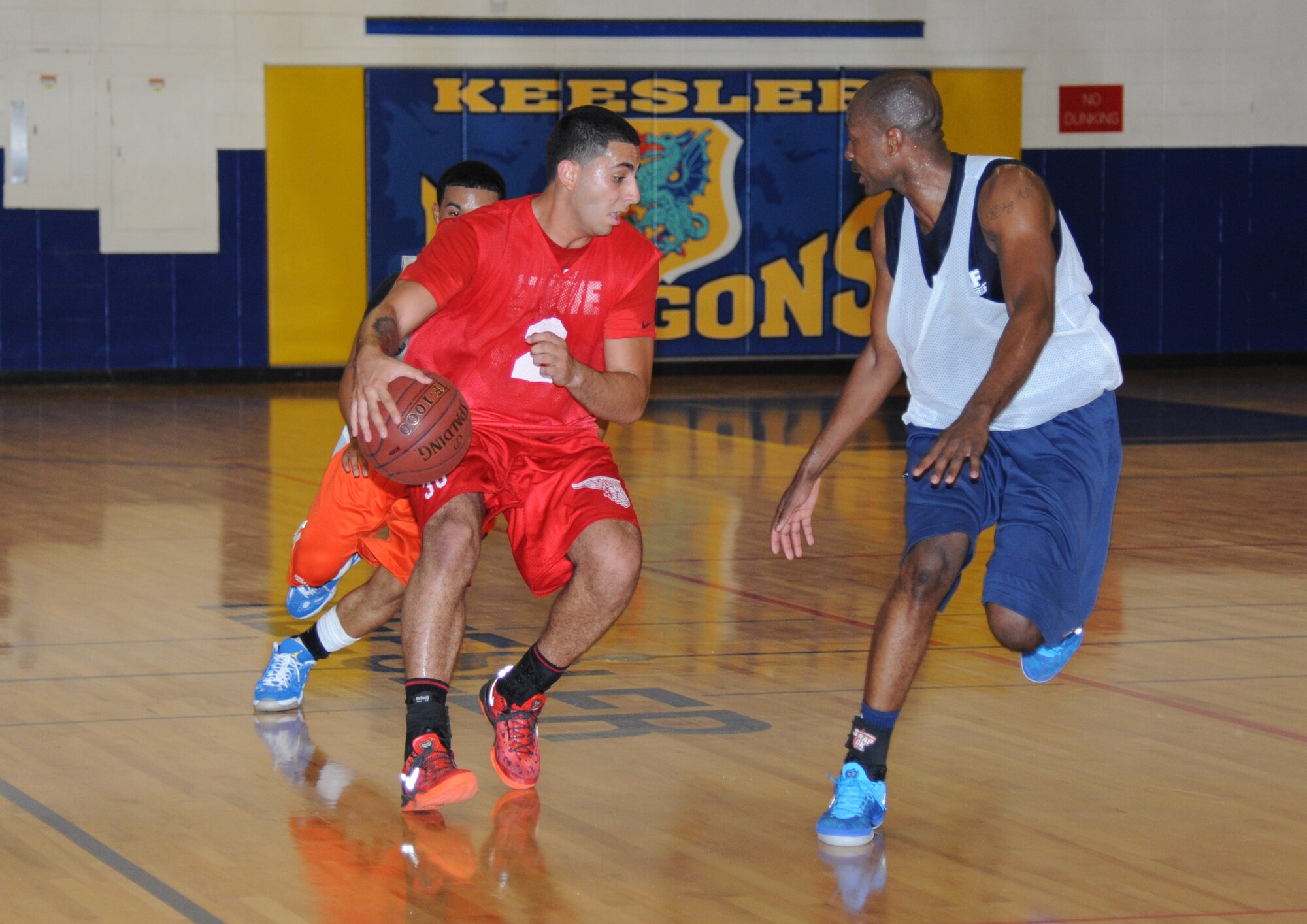 Tarek Salem, 81st Communications Squadron, dribbles down the court with Mario McKnight and Alvin Holmes, 81st Medical Group, play close defense during an intramural basketball game Aug. 12, 2013, at the Blake Fitness Center, Keesler Air Force Base, Miss.  The 81st MDG defeated the 81st CS, 59-48.  (U.S. Air Force photo by Kemberly Groue)