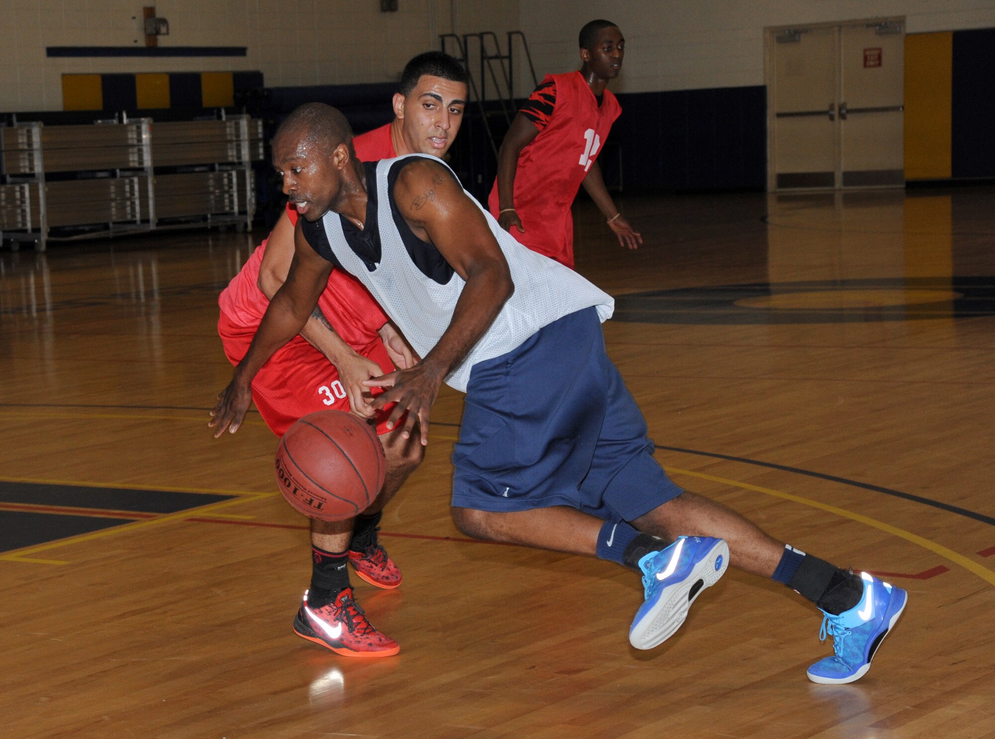 Alvin Holmes, 81st Medical Group, drives the ball past Tarek Salem, 81st Communications Squadron, while his team-mate, Parris Brown, plays defense during an intramural basketball game Aug. 12, 2013, at the Blake Fitness Center, Keesler Air Force Base, Miss.  The 81st MDG defeated the 81st CS, 59-48.  (U.S. Air Force photo by Kemberly Groue)