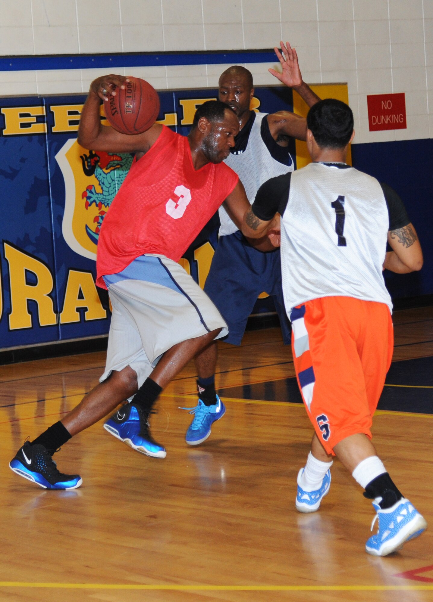 Ternae Riley, 81st Communications Squadron, drives the basketball between Alvin Holmes and Mario McKnight, 81st Medical Group, for two points during an intramural basketball game Aug. 12, 2013, at the Blake Fitness Center, Keesler Air Force Base, Miss.  The 81st MDG defeated the 81st CS, 59-48.  (U.S. Air Force photo by Kemberly Groue)