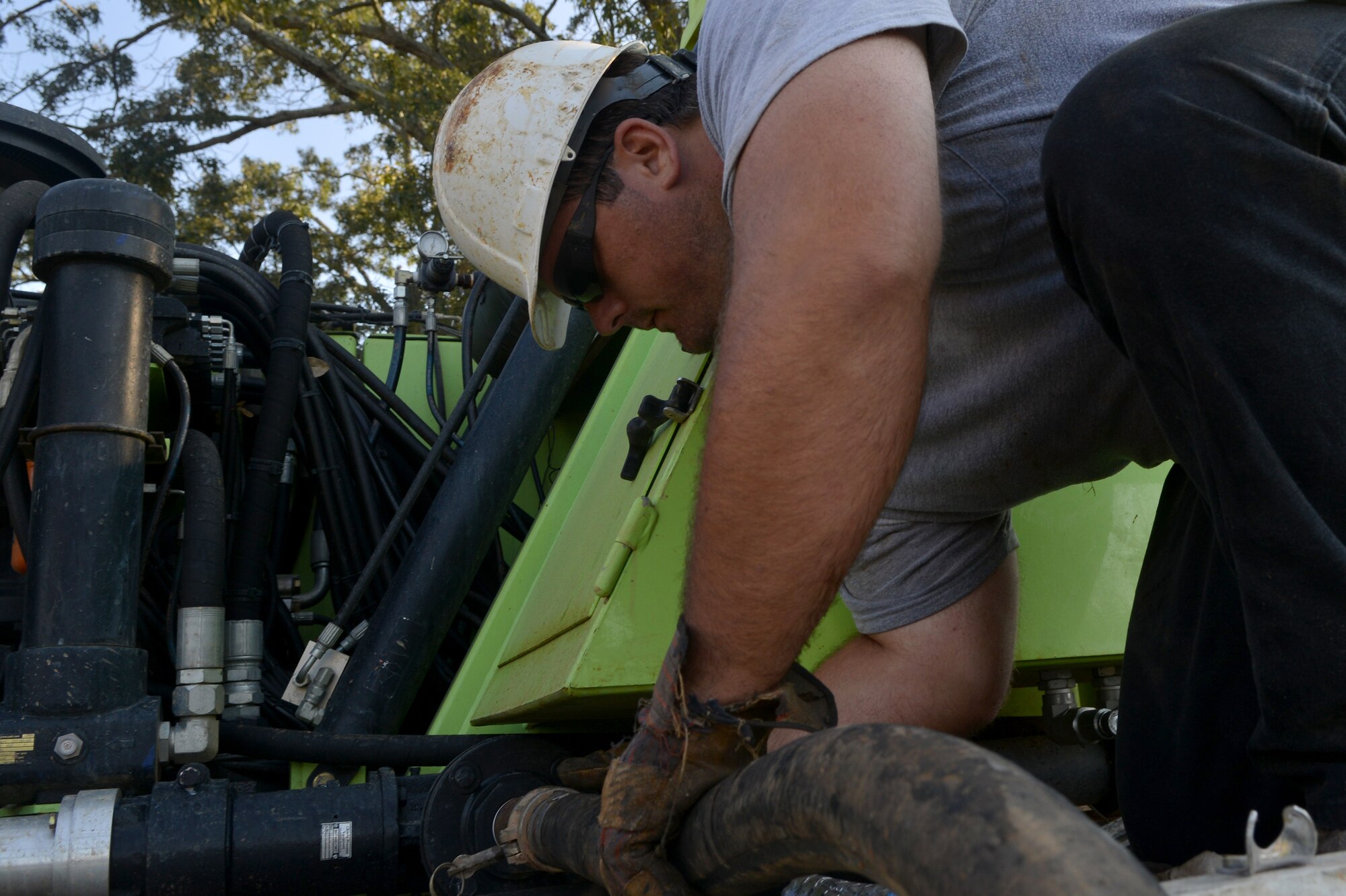 Corey Preston, URS Corporation drill helper, connects a tube to the drilling rig as part of the draining process, Shaw Air Force Base, S.C., Aug. 12, 2013. Scheduled well maintenance will take place for the next two weeks on base. (U.S. Air Force photo by Airman 1st Class Ashley L. Gardner/Released)