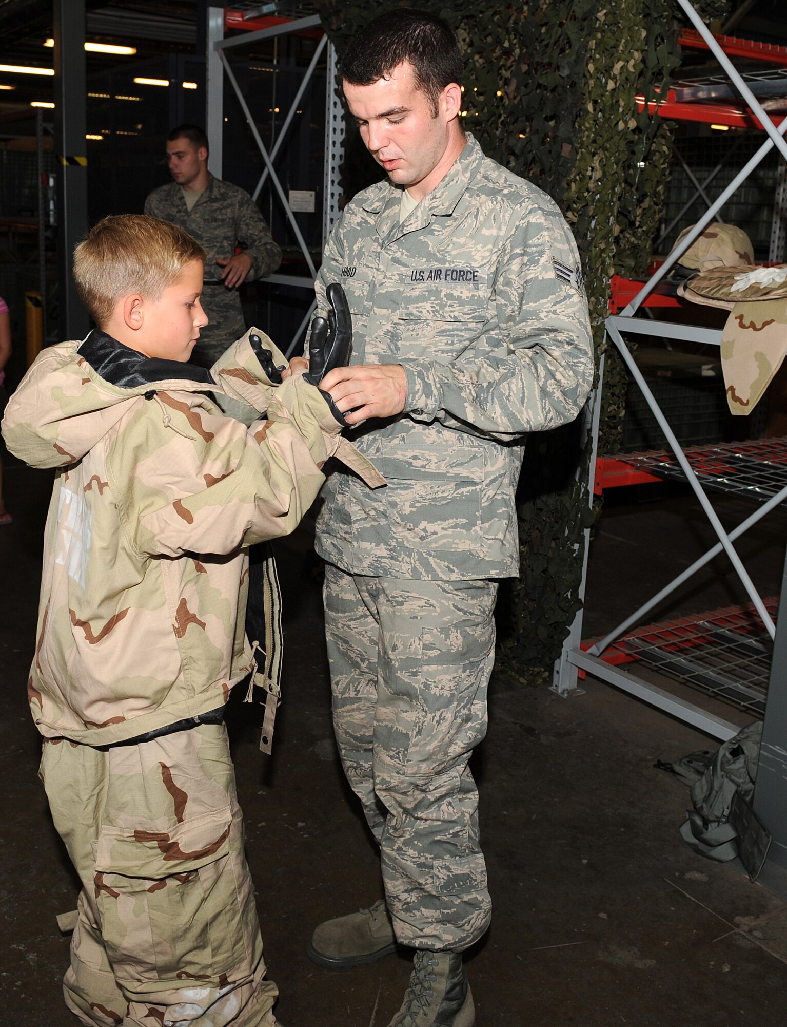 U.S. Air Force Senior Airman Jonathan Hood, 633rd Logisitics Readiness Squadron individuial protective equipment journeyman, dresses Derek Percivalle in protective gear during Operation Hero at Langley Air Force Base, Va., Aug. 7, 2013. Hood was one of many volunteers who helped children see the aspects of deployment requirements a Service member might encounter. (U.S. Air Force photo by Senior Airman Brittany Paerschke-O’Brien/Released)