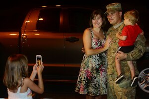 U.S. Air Force Staff Sgt. Robert Hernandez, 633rd Civil Engineer Squadron engineer technician, poses with his wife and son while his 7-year-old daughter Alyssa takes a photo during the 633rd CES redeployment at Langley Air Force Base, Va., Aug. 7, 2013. Friends and family welcomed the team home after a deployment to Afghanistan. (U.S. Air Force photo by Staff Sgt. Ashley Hawkins/Released)