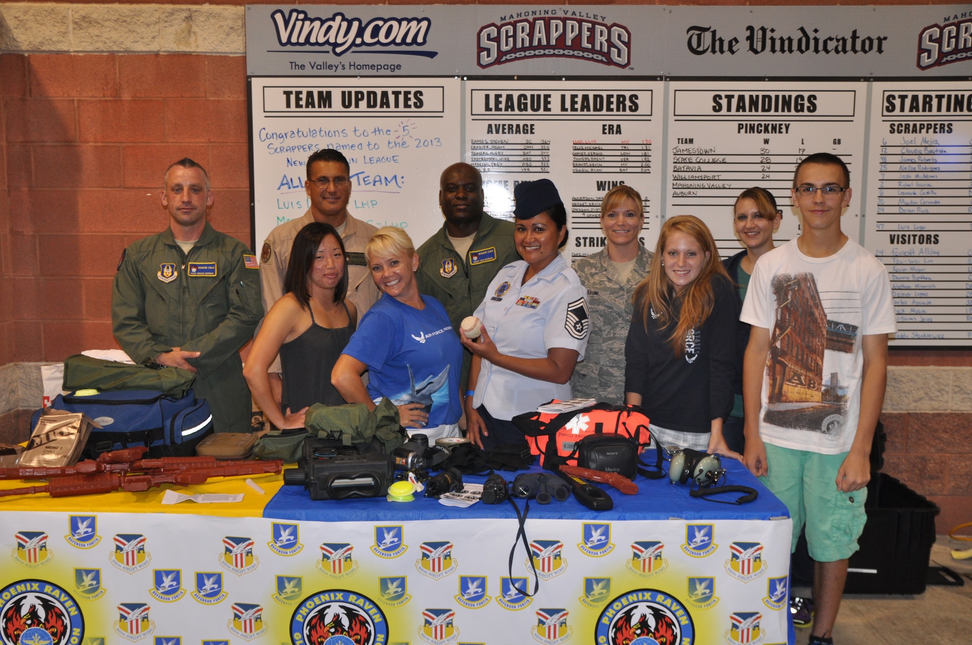 A group representing Youngstown Air Reserve Station (YARS), Ohio stands behind a concourse table display during a minor league baseball game between the Cleveland Indians Class A affiliate Mahoning Valley Scrappers and the Lowell Spinners at Eastwood Field here, August 7, 2013. Nearly 200 Citizen Airmen along with their families, friends and co-workers were in attendance and individuals from the 910th Airlift Wing, based at nearby YARS, were involved in many game night activities. U.S. Air Force photo by Master Sgt. Bob Barko Jr.