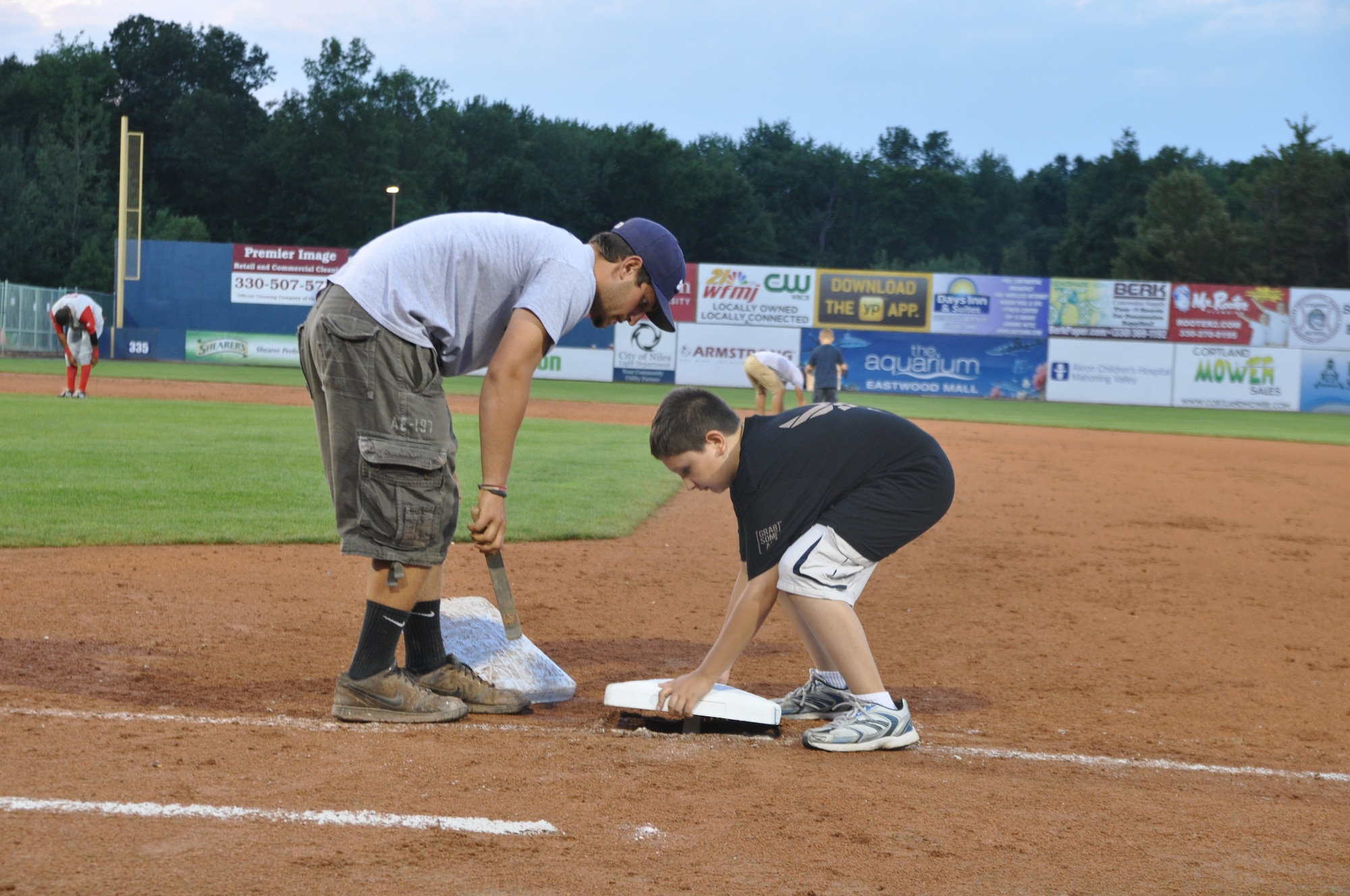 Nick Geraci, a game night Public Affairs event assistant, works to switch out the first base bag during a minor league baseball game between the Cleveland Indians Class A affiliate Mahoning Valley Scrappers and the Lowell Spinners at Eastwood Field here, August 7, 2013. Nearly 200 Citizen Airmen along with their families, friends and co-workers were in attendance and representatives from the 910th Airlift Wing, based at nearby Youngstown Air Reserve Station, Ohio, were involved in many game night activities. U.S. Air Force photo by Master Sgt. Bob Barko Jr.