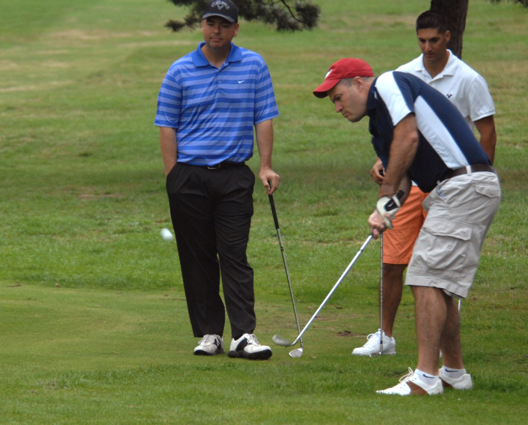 U.S Air Force Col. Kenneth T. Bibb, 100th Air Refueling Wing commander, right, chips the ball onto the green Aug. 9, 2013, during the Focus on Mentorship golf tournament at the Breckland Pines Golf Club on RAF Lakenheath, England. The golfers were playing in a scramble format, where all members of the team hit from the same spot throughout the hole, using the best shot each time to determine the location of the next shot.  The event focused on discussing different aspects of mentoring Airmen in a casual environment. (U.S. Air Force photo by Airman 1st Class Dillon Johnston/Released)