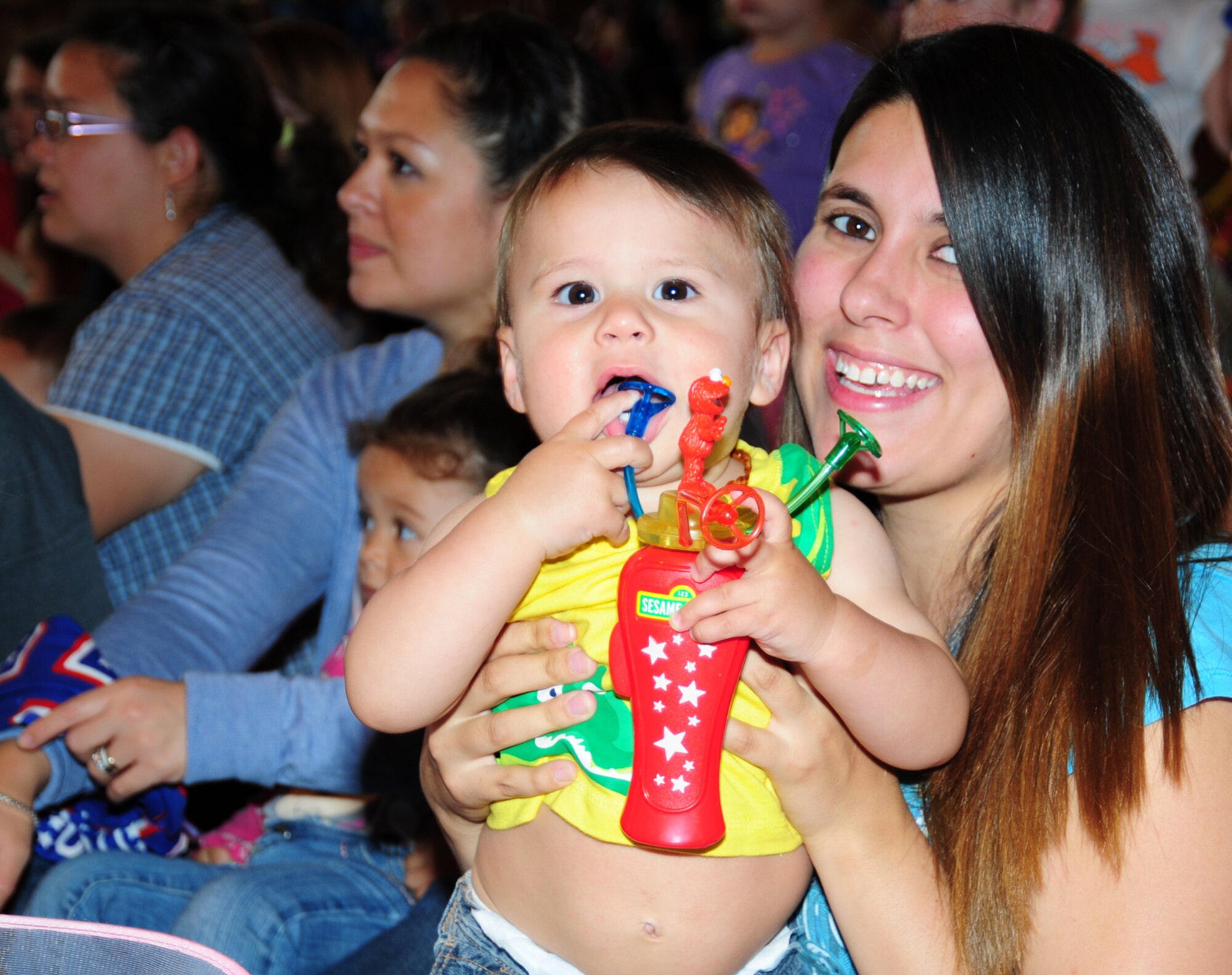Wyatt Kiniry, 10 months, plays with his toy as he and his mom Donna Kiniry, 100th Logistics Readiness Squadron spouse, have fun at the Sesame Street/United Services Organization Experience for Military Families tour Aug. 12, 2013, in the North Side Fitness Center  on RAF Mildenhall, England. The tour brought Elmo, Cookie Monster, Grover, Rosita and Katie to visit children at bases around the world. More than 1,100 people attended the event. (U.S. Air Force photo by Karen Abeyasekere/Released)