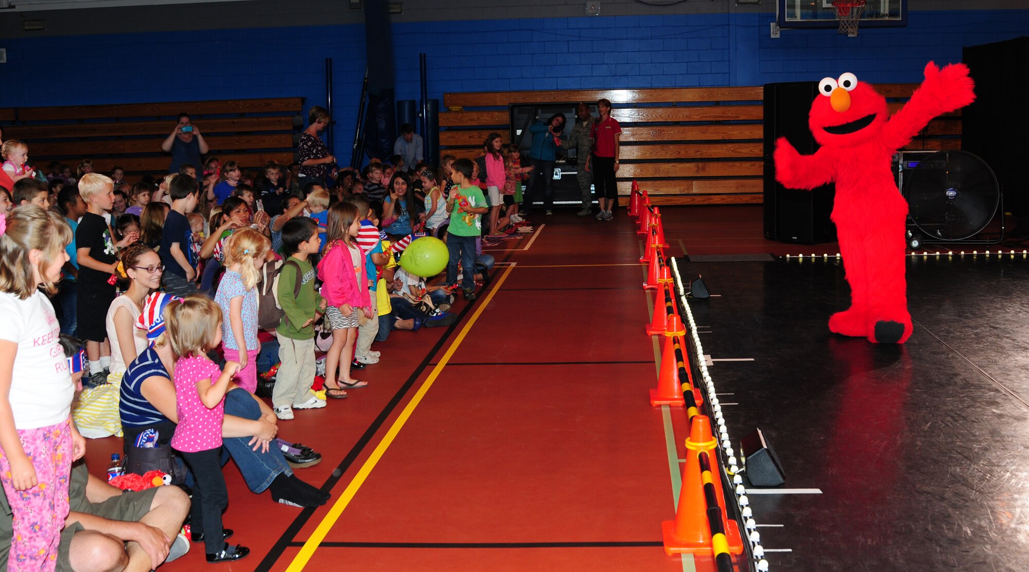 Children join in with the “Elmo shuffle” as Elmo and other Sesame Street characters demonstrate during the Sesame Street/United Services Organization Experience for Military Families Aug. 12, 2013, in the North Side Fitness Center on RAF Mildenhall, England. The tour visited military members and their families both stateside and around the world. The 2013 tour focused on the impact a military lifestyle has on children. (U.S. Air Force photo by Karen Abeyasekere/Released)