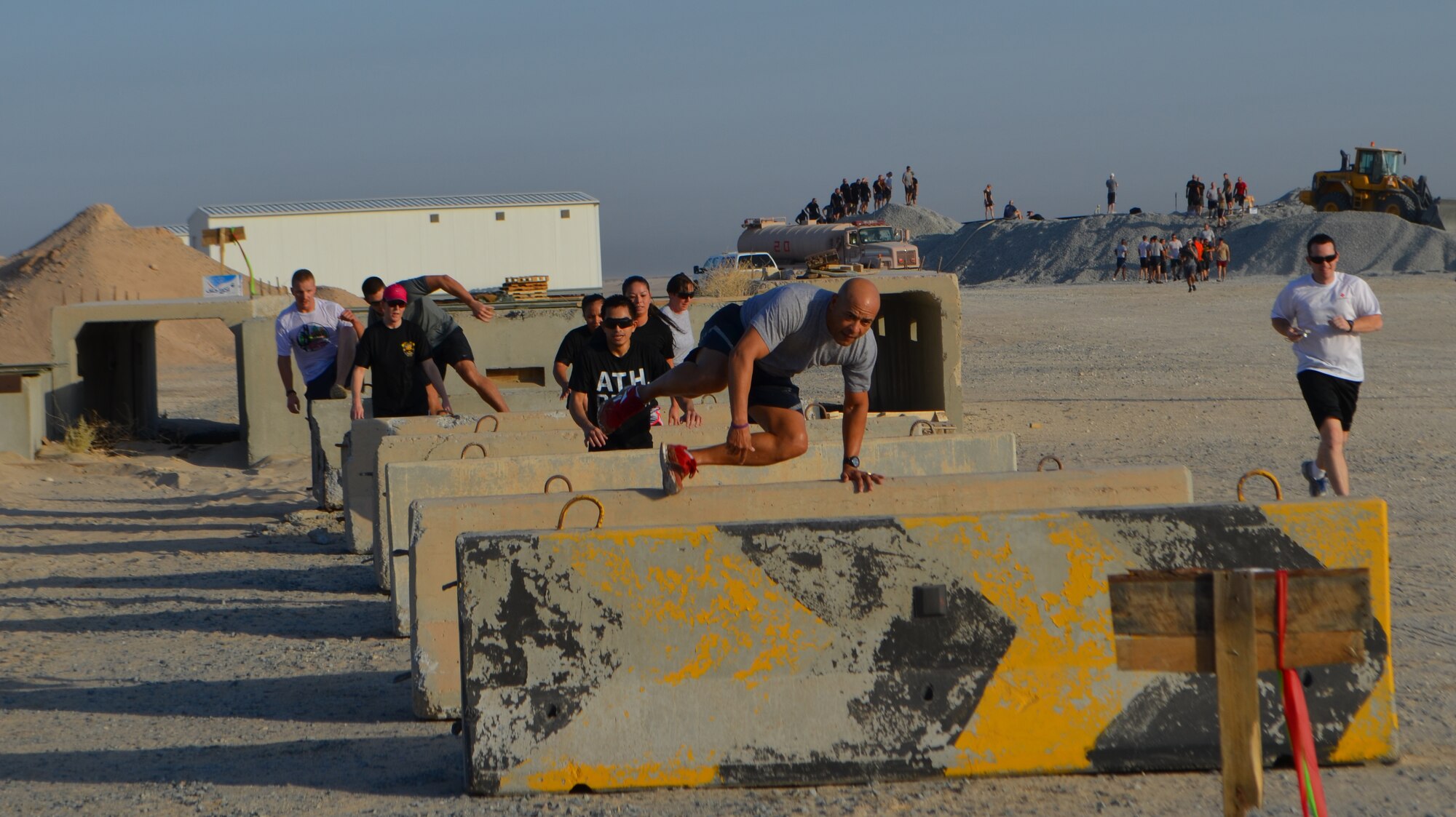 Participants in a firefighter memorial adventure challenge jump “hurdles” Aug. 10, 2013 at the 386thh Air Expeditionary Wing in an undisclosed location in Southwest Asia.  More than 150 people participated in the event which included nine obstacles, an over three-mile run, 19 pull-ups, 19 push-ups and 19 burpees.  The challenge raised more than $1000 that will be donated to the memorial fund for the 19 firefighters who lost their lives in the Yarnell Hill fire in Arizona in June, 2013.  (Courtesy photo)