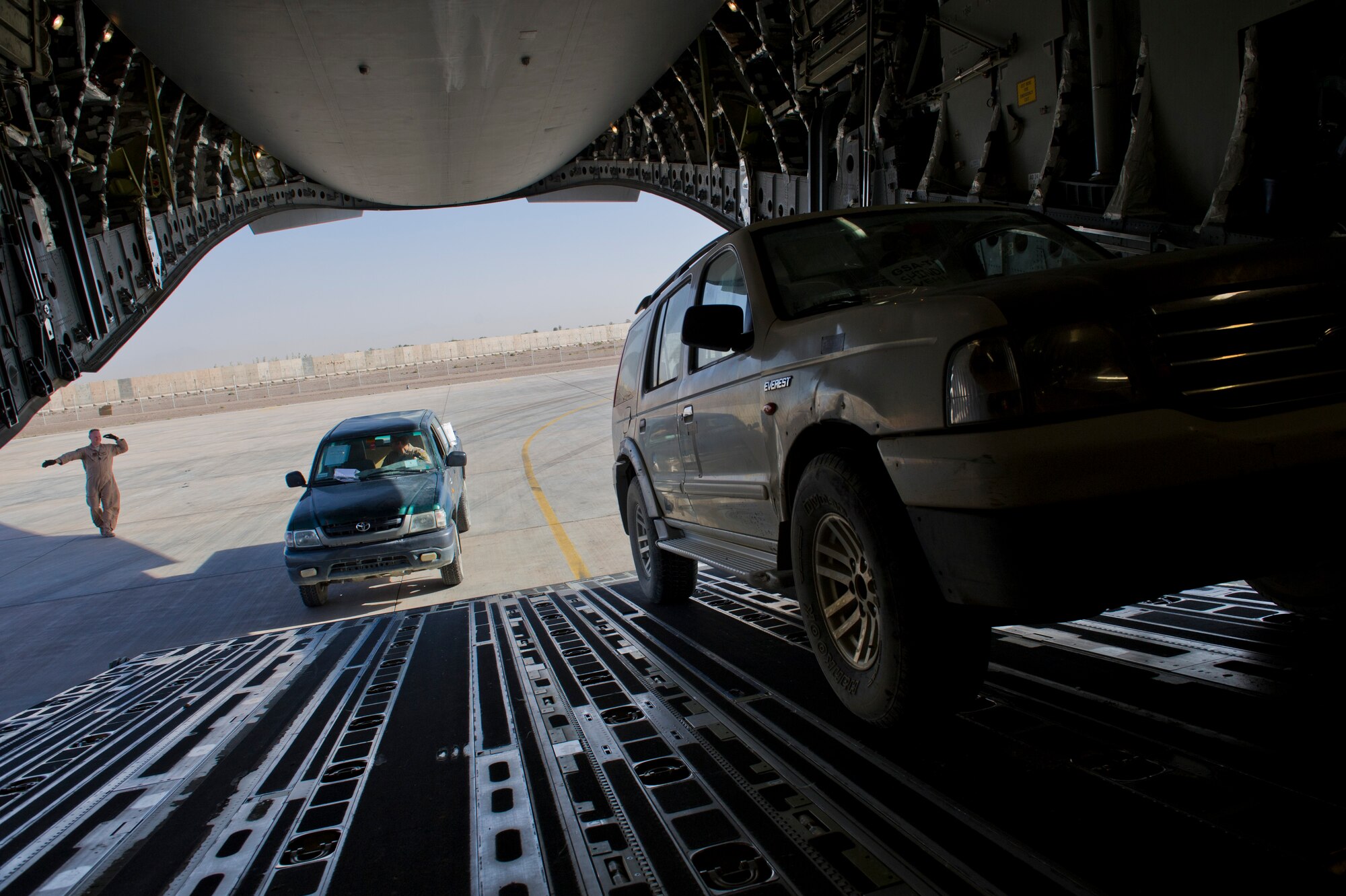 U.S. Air Force Tech. Sgt. Gary Washington, center, 316th Expeditionary Airlift Squadron C-17 Globemaster III loadmaster, off-loads vehicles during an airlift mission, July 25, 2013, Forward Operating Base Shindand Air Base, Herat, Afghanistan. The C-17 is capable of rapid strategic and tactical delivery of troops and any type of cargo around the Central Command area of reasonability. The aircraft can perform airlift, airdrop, and transport ambulatory patients during aeromedical evacuations when required. (U.S. Air Force photo/Staff Sgt. Marleah Miller)
