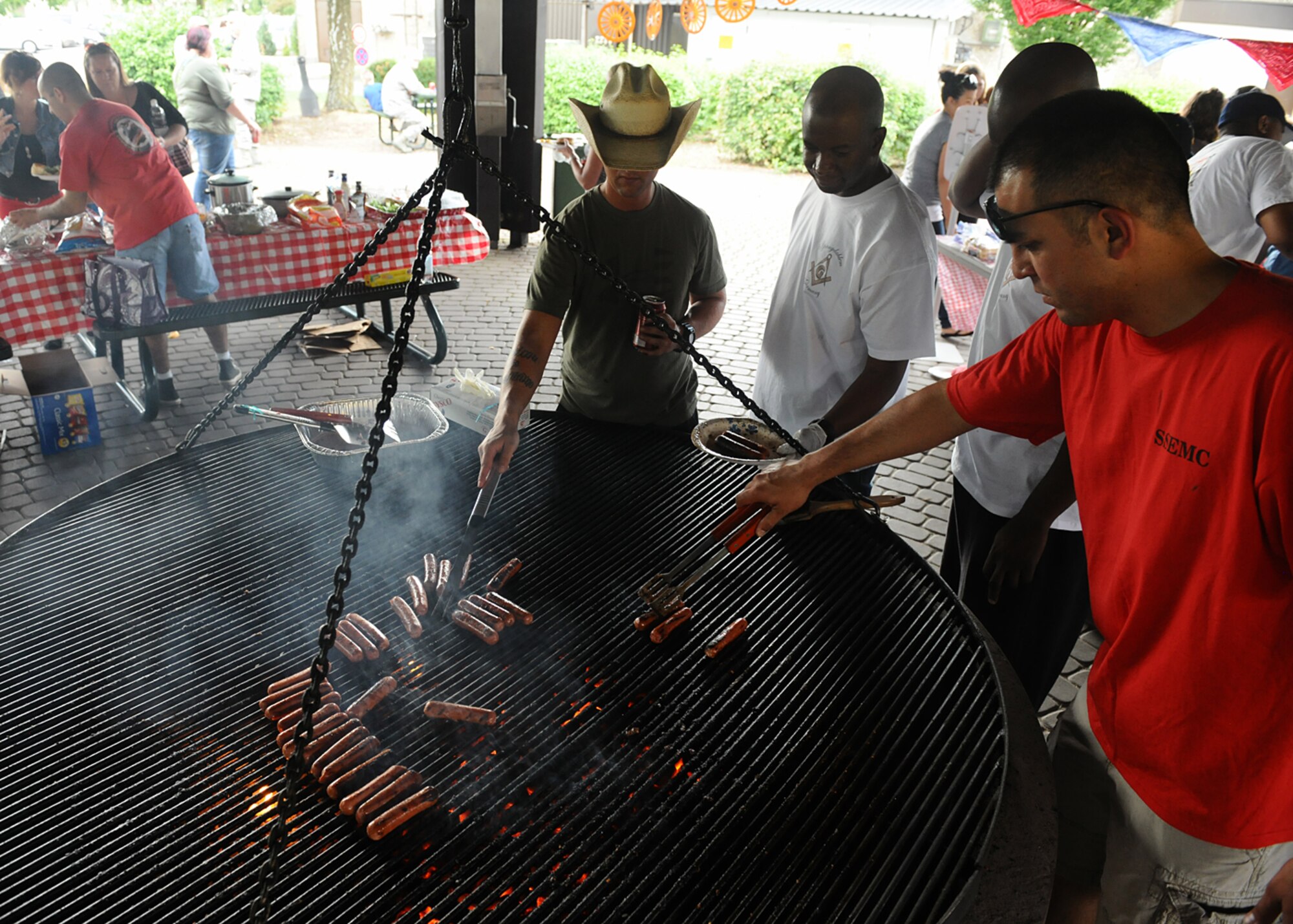 SPANGDAHLEM AIR BASE, Germany -- Volunteers barbecue hotdogs for families of deployed members during the 52nd Force Support Squadron Airman and Family Readiness Center's Deployment Dinner Aug. 8 at the bowling alley pavilion. The volunteers were from the Spangdahlem Spouses and Enlisted Members Club, the organization which sponsored this deployment dinner. The dinner is open to all Spangdahlem members who currently have a family member deployed. (U.S. Air Force photo by Staff Sgt. Daryl Knee/Released)