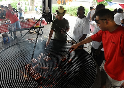SPANGDAHLEM AIR BASE, Germany -- Volunteers barbecue hotdogs for families of deployed members during the 52nd Force Support Squadron Airman and Family Readiness Center's Deployment Dinner Aug. 8 at the bowling alley pavilion. The volunteers were from the Spangdahlem Spouses and Enlisted Members Club, the organization which sponsored this deployment dinner. The dinner is open to all Spangdahlem members who currently have a family member deployed. (U.S. Air Force photo by Staff Sgt. Daryl Knee/Released)