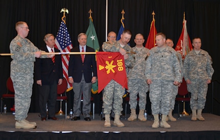 1st Sgt. Joshua D. Entzel, center, of Bismarck, N.D., places a streamer on the guidon for the North Dakota Army National Guard's 1st Battalion, 188th Air Defense Artillery Regiment during an April 28 ceremony at the Alerus Center in Grand Forks, N.D.