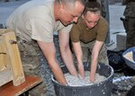 Tech. Sgt. Benjamin Griffin and Airman 1st Class MelissaBradley mix shredded paper, sawdust and water to make fuel pucks and bricks May3, 2013, at Kabul International Airport, Afghanistan. Griffin is with the 440thAir Expeditionary Advisory Squadron and Bradley is with the 439th AEAS.
